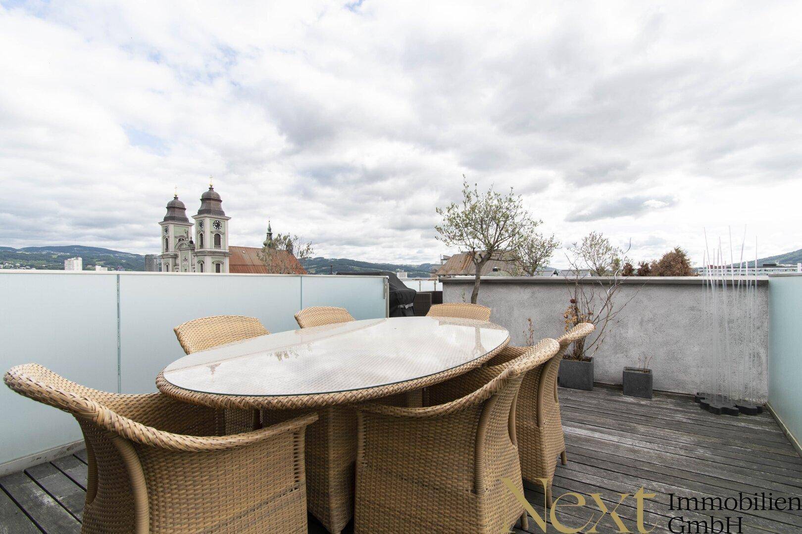Gemütliche Dachterrasse mit Esstisch und Stühlen, ideal für Mahlzeiten im Freien mit Stadtblick.