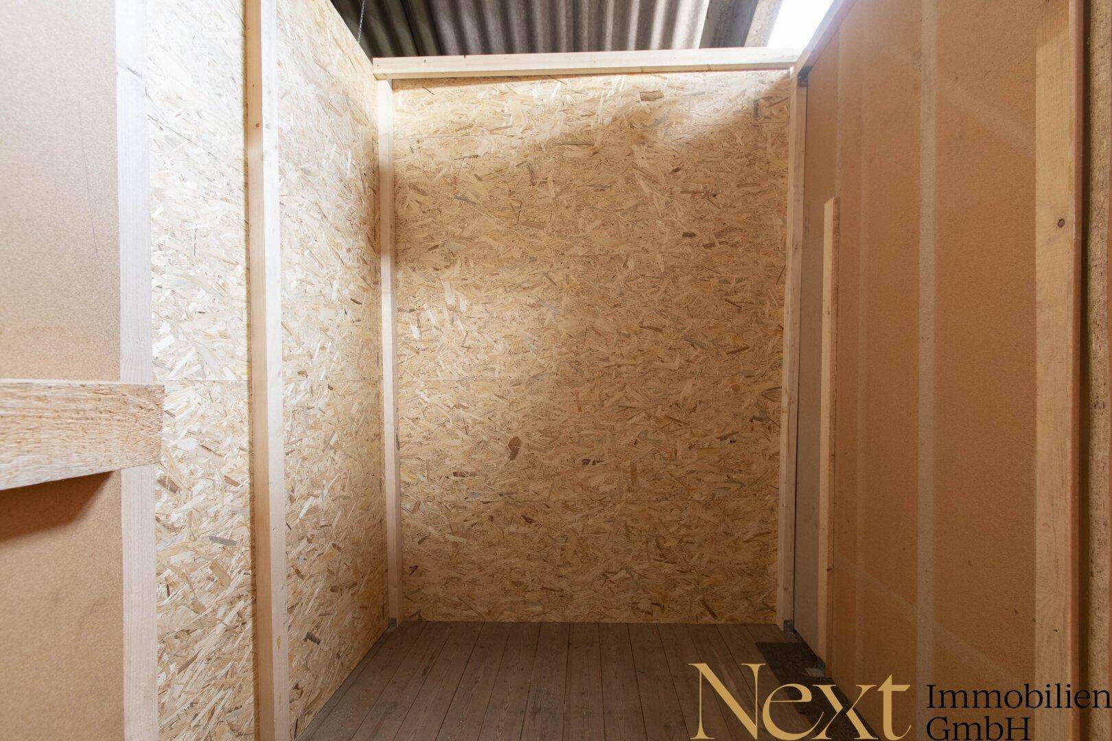 Kleiner, unfertiger Innenraum mit Wänden aus OSB-Platten und einem einfachen Holzfußboden.