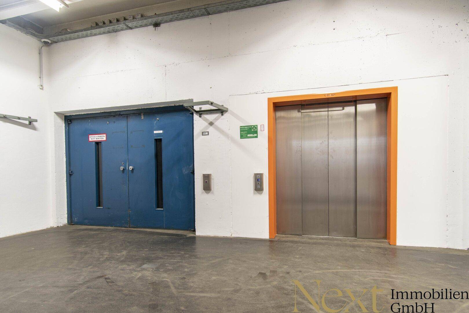 Industrieller Flur mit einem großen Lastenaufzug und einer weiteren Zugangstür.