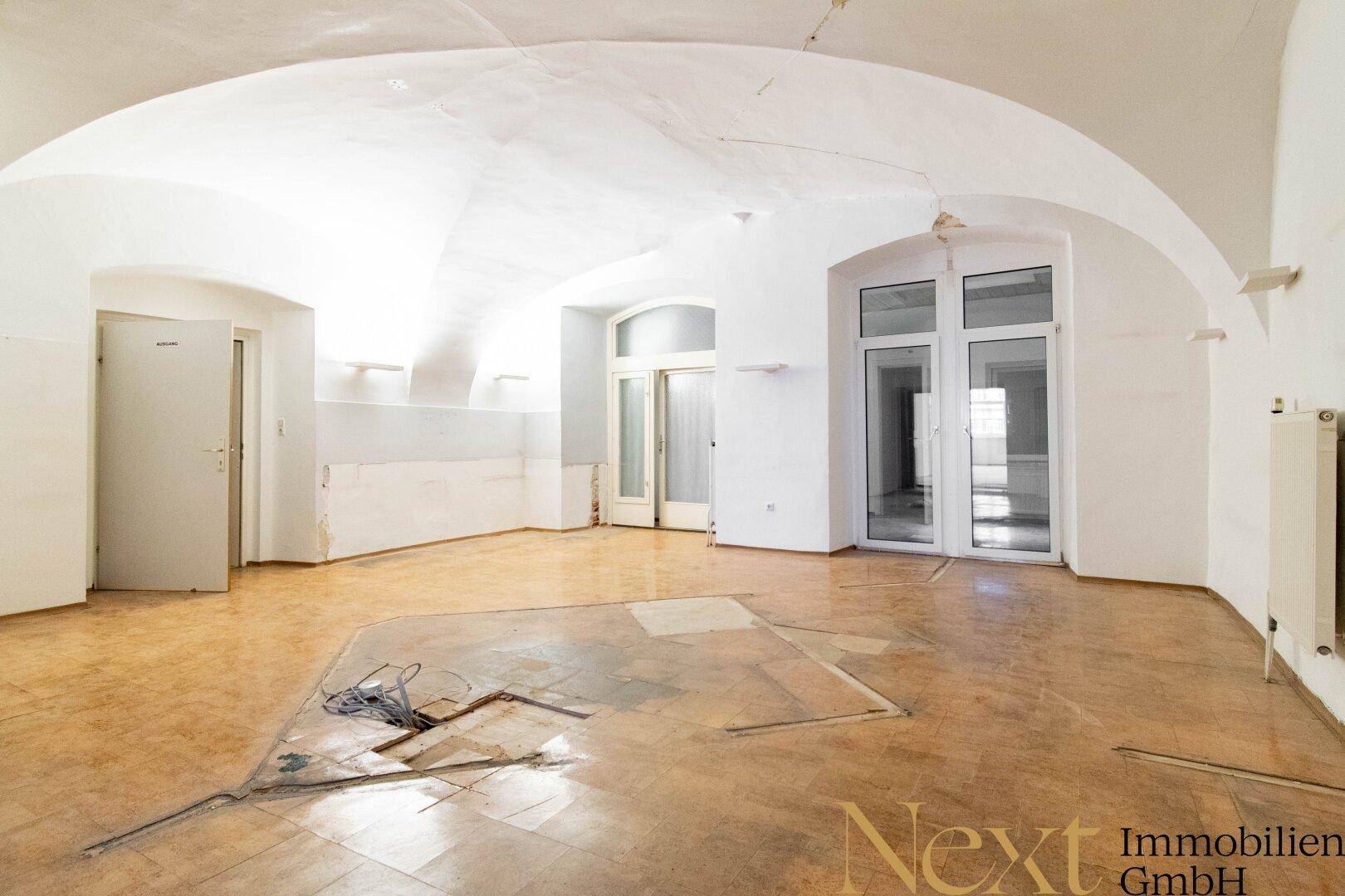 Großer Raum mit beeindruckenden Gewölbedecken und Fenstertüren, der sich in einem Zustand für den Abriss befindet.