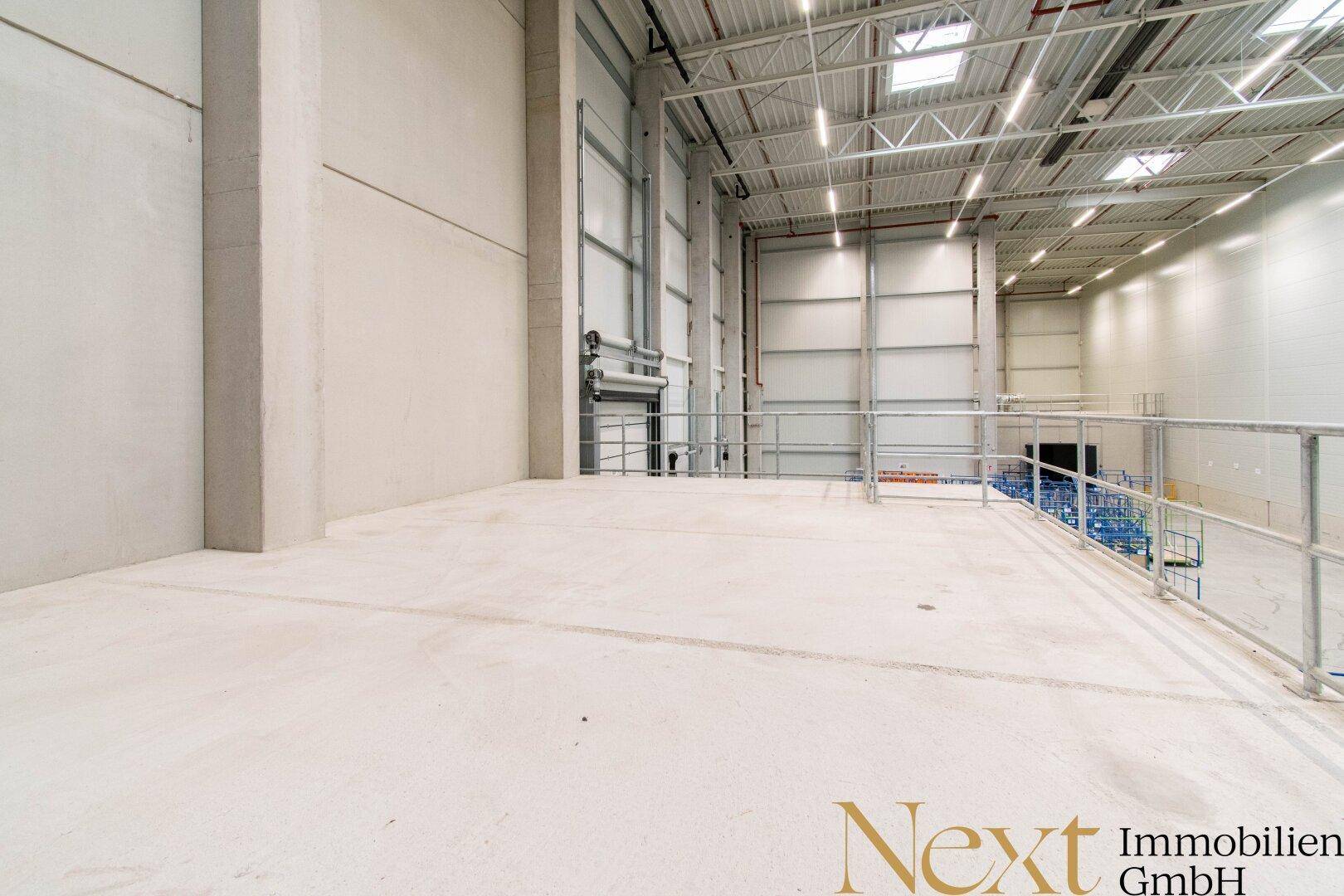 Große Lagerhalle mit hohen Decken, Betonboden und Metallkonstruktionen.