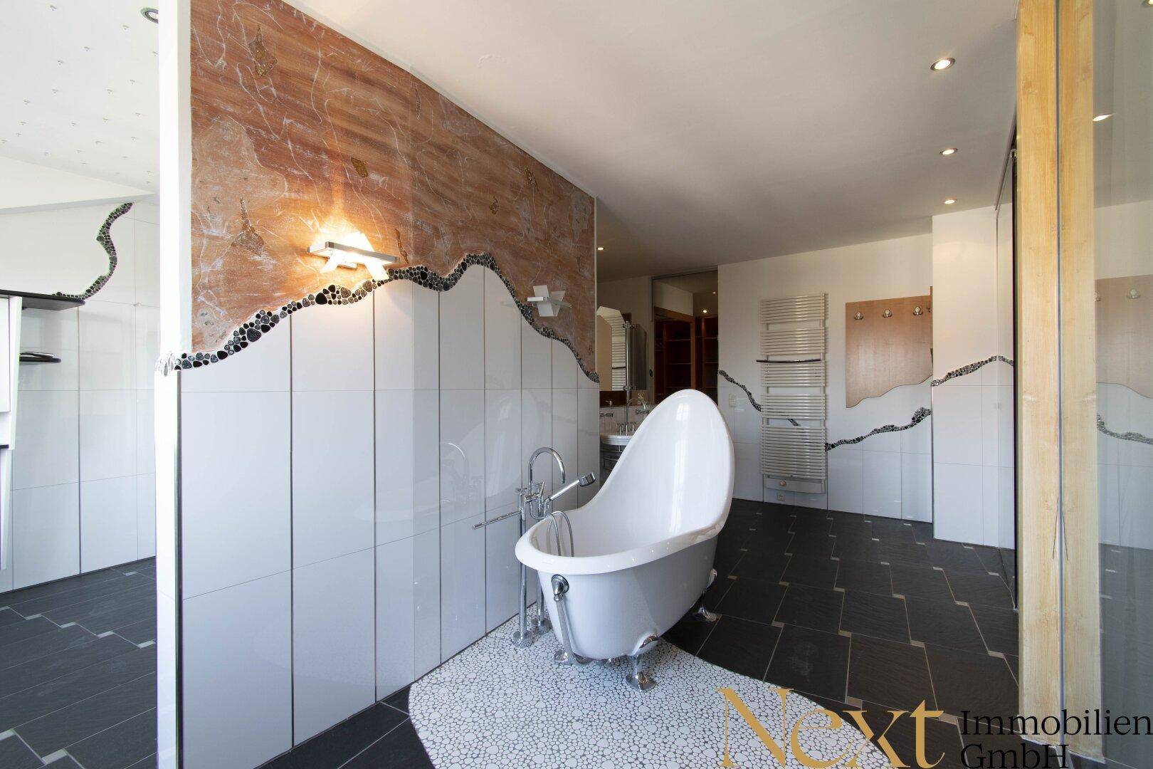Luxuriöses Badezimmer mit freistehender Badewanne, modernen Fliesen und dekorativen Wandelementen.