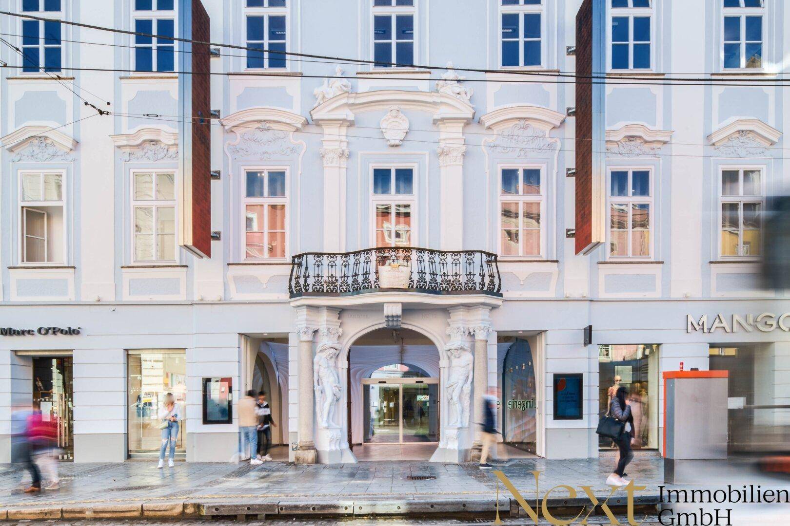 Historisches Gebäude mit hellblauer Fassade, kunstvollen Verzierungen und einem kleinen Balkon über dem Eingang.