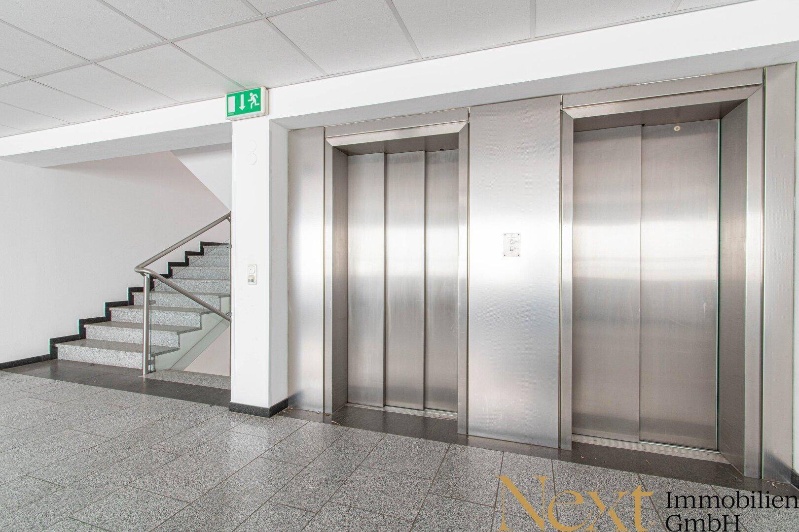 Lobbybereich mit zwei Aufzügen und einer Treppe, die zu den oberen Etagen führt.