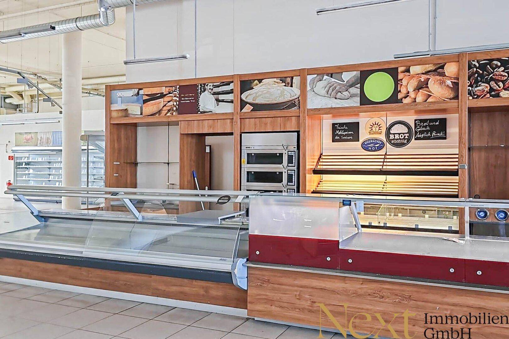 Bäckereitheke mit Auslagen und Backöfen in einem großen Verkaufsraum, bereit zur Wiedereröffnung.