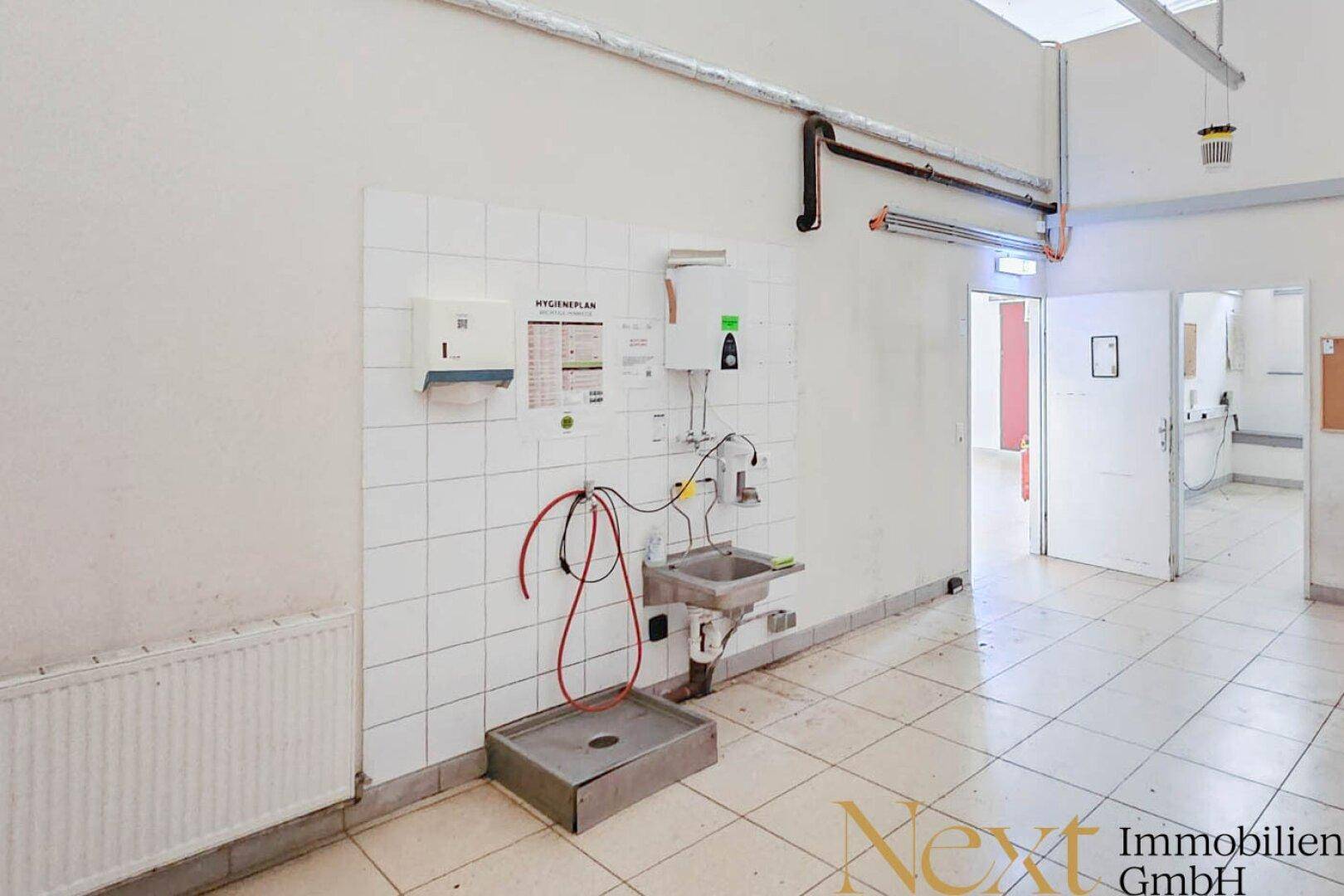 Gefliester Wirtschaftsraum mit Waschbecken und Hygieneplan, ideal für Reinigungs- oder Vorbereitungsarbeiten.