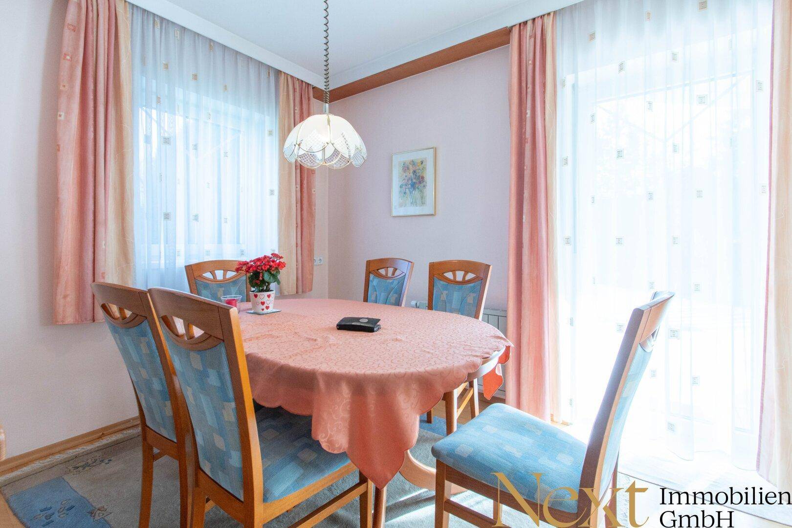Heller Essbereich mit großem Holztisch, passenden Stühlen und Zugang zum Außenbereich.