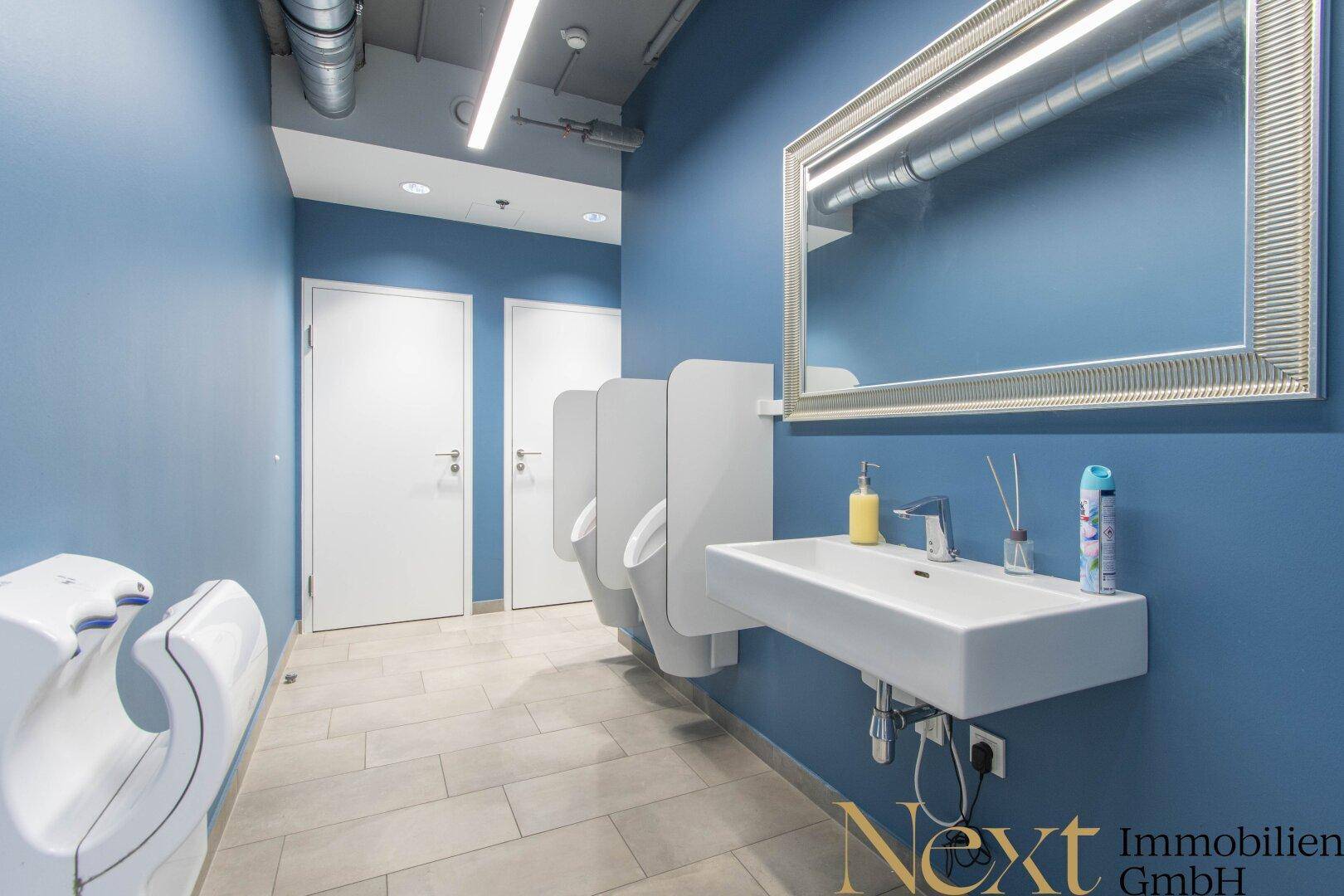 Modernes Herrenbad mit blauen Wänden, mehreren Urinalen, einem Waschbecken und praktischen Händetrocknern.