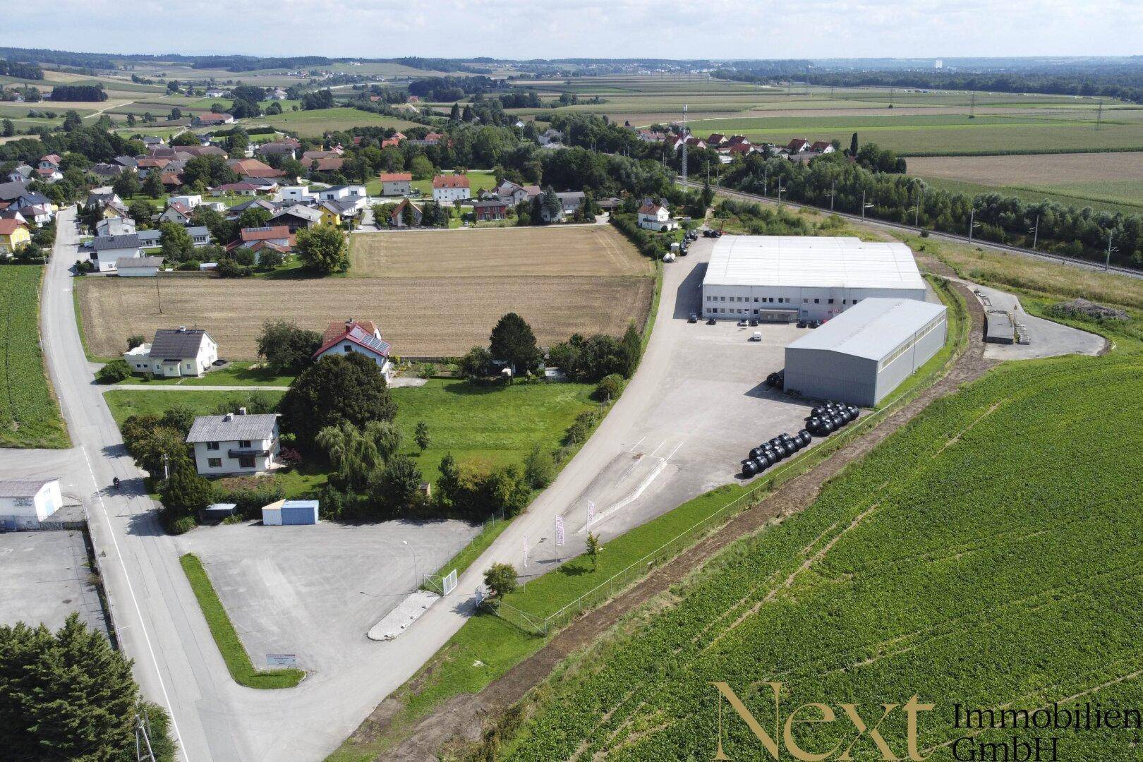 Panoramische Luftaufnahme des Industriegebiets, eingebettet in eine ländliche Landschaft mit Feldern und einem Dorf.