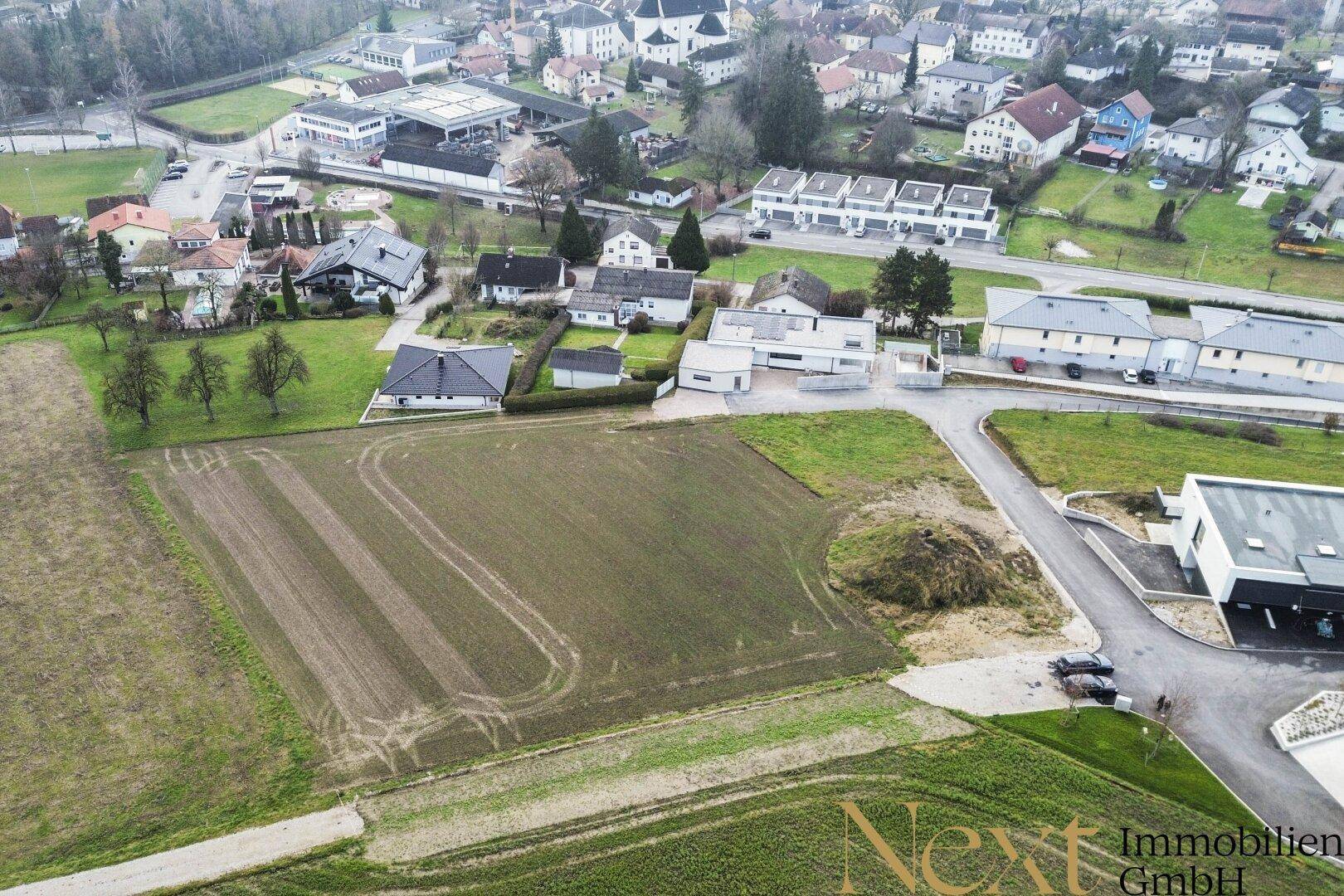 Weitläufige Luftaufnahme eines Baugrundstücks mit Blick auf die umliegende ländliche Bebauung und Felder.