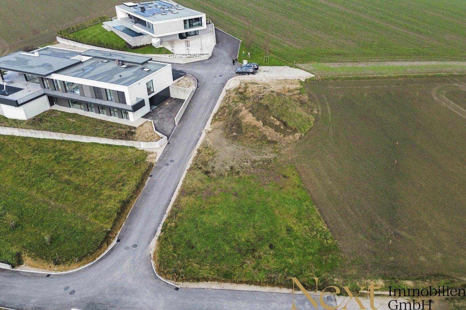 Übersicht des Baugrundstücks aus der Vogelperspektive, umgeben von Feldern und modernen Wohnhäusern.