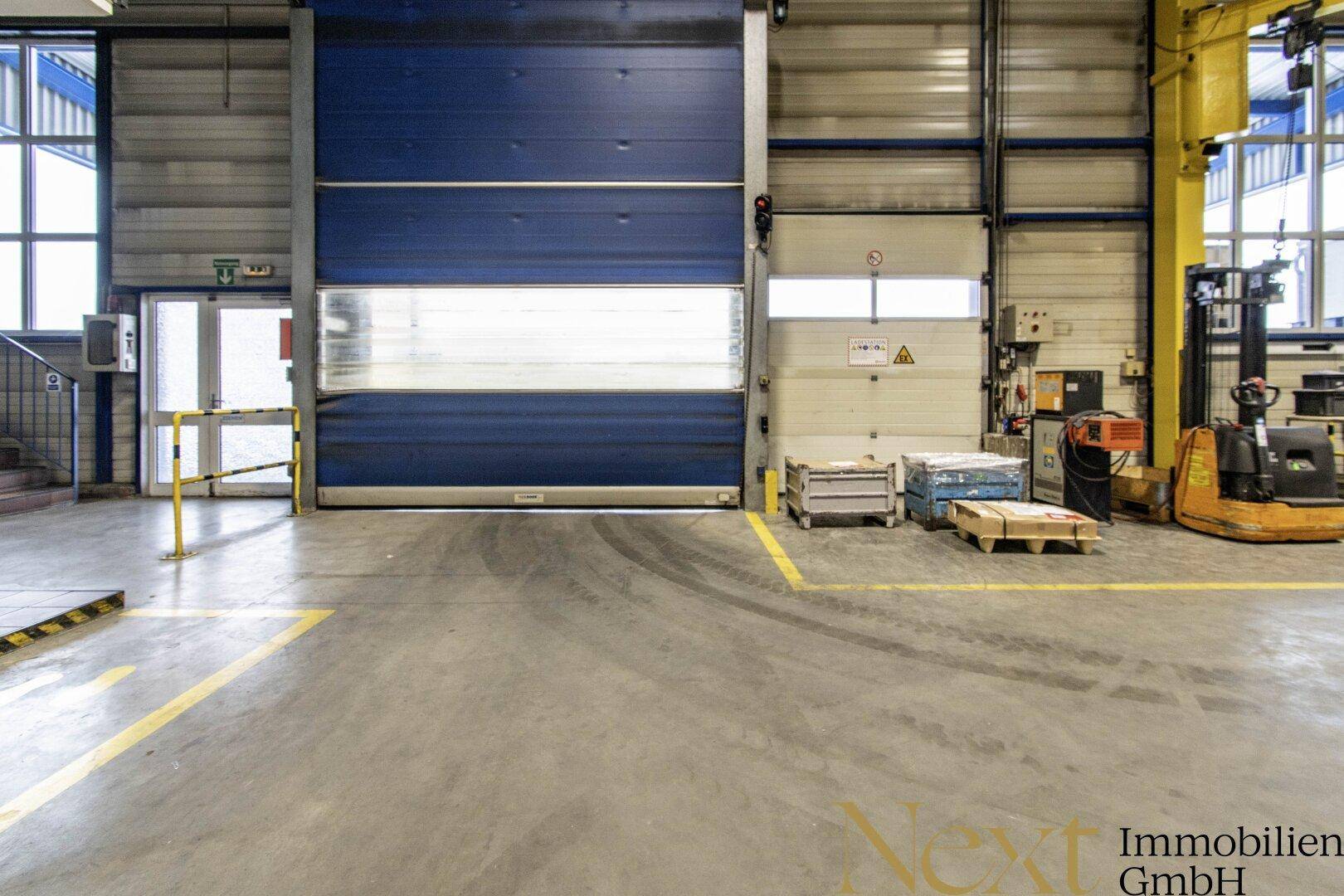 Große Laderampe mit einem blauen Rolltor, bereit für den Warenumschlag in der Industriehalle.