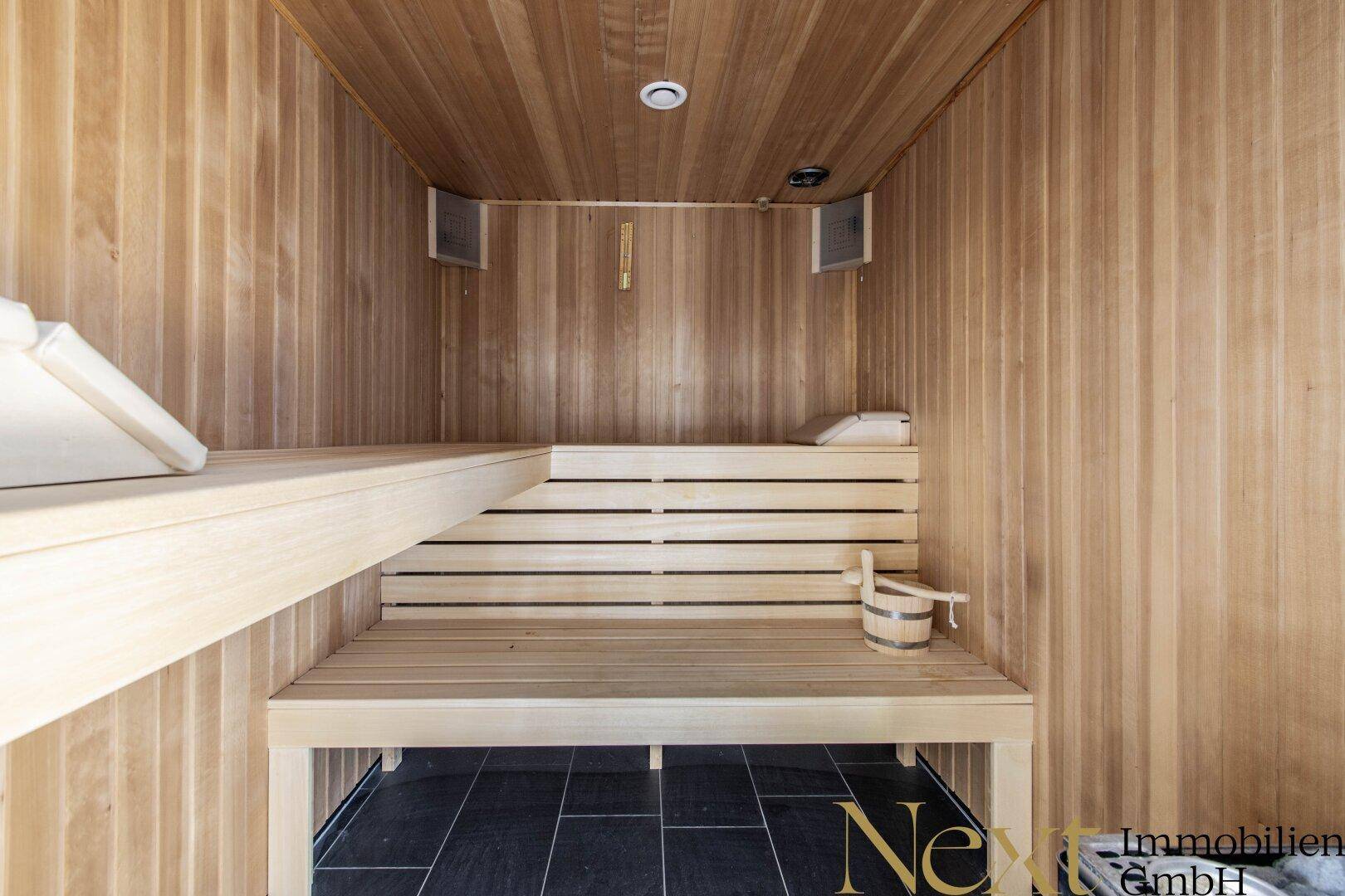 Gemütliche Holzsauna mit Bänken und traditionellem Eimer, bereit zur Entspannung.