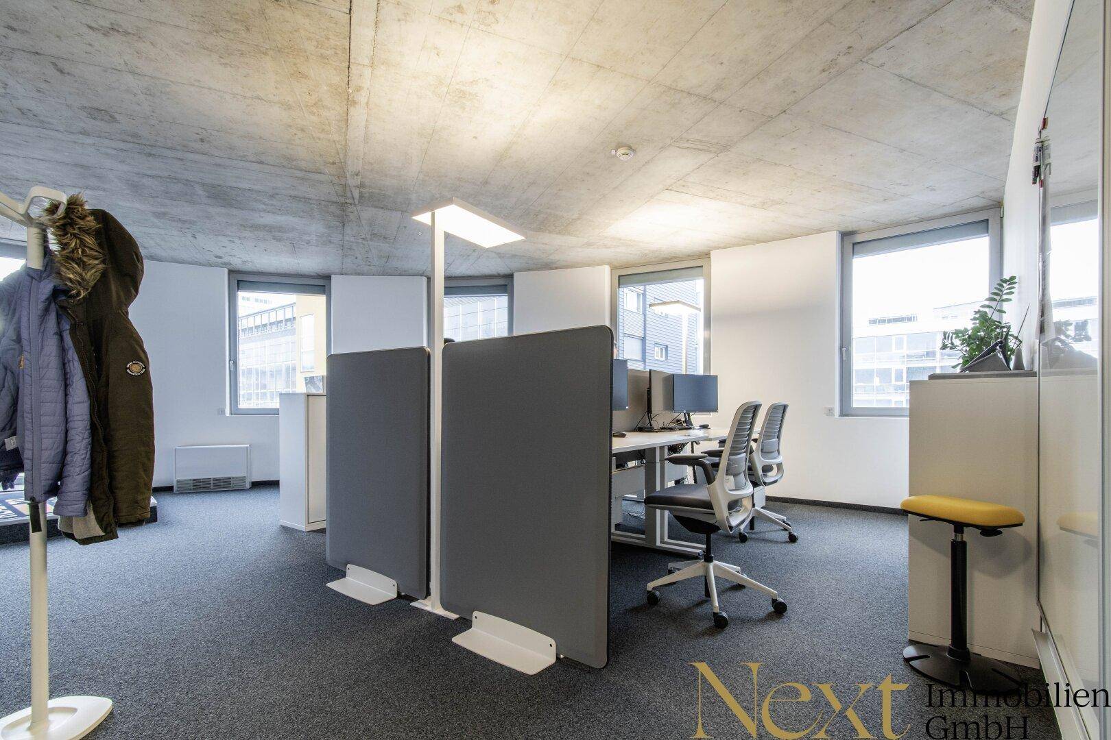 Detailansicht eines modernen Bürobereichs mit ergonomischen Arbeitsplätzen und schallabsorbierenden Trennwänden.