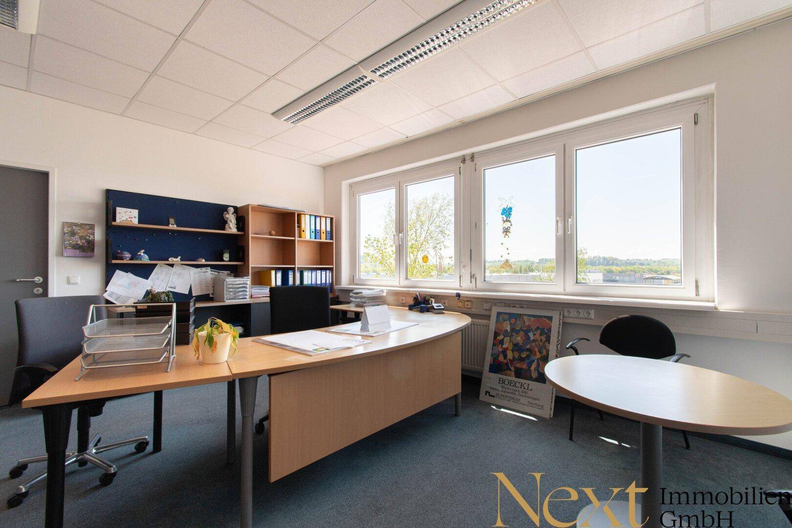 Geräumiges Büro mit Teppichboden, großen Fenstern und Blick auf die umliegende Landschaft.