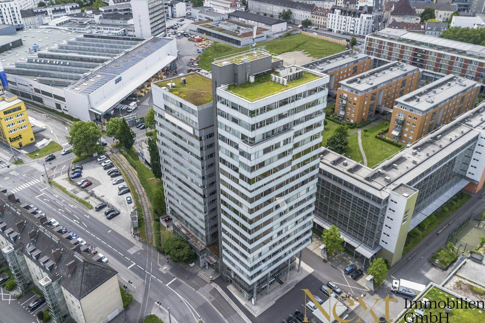 Luftaufnahme von zwei modernen Bürogebäuden mit begrünten Dächern inmitten einer städtischen Umgebung.