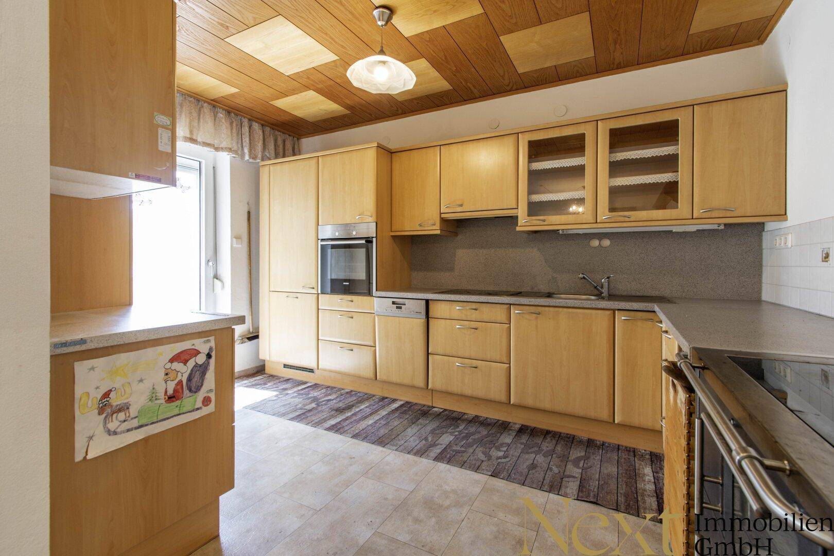 Funktionale Küche mit Holzfronten, Einbaugeräten und gefliestem Boden.