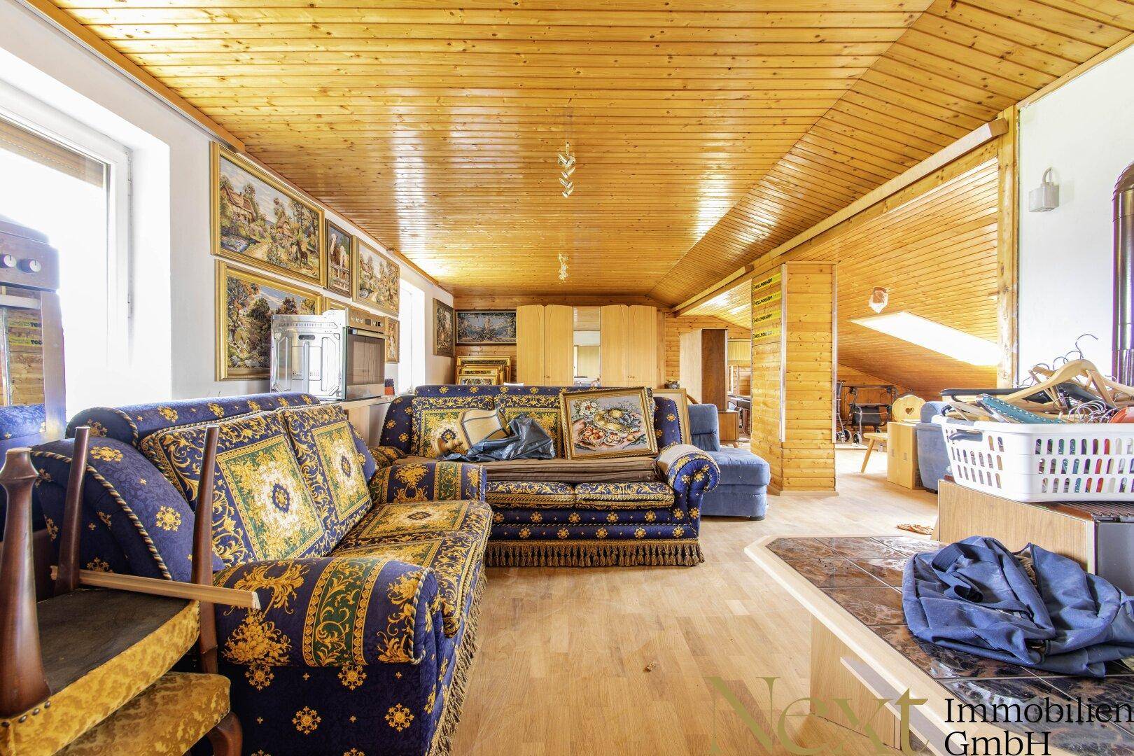 Geräumiger Wohnbereich im Dachgeschoss mit Holzboden und traditionellen Sofas.