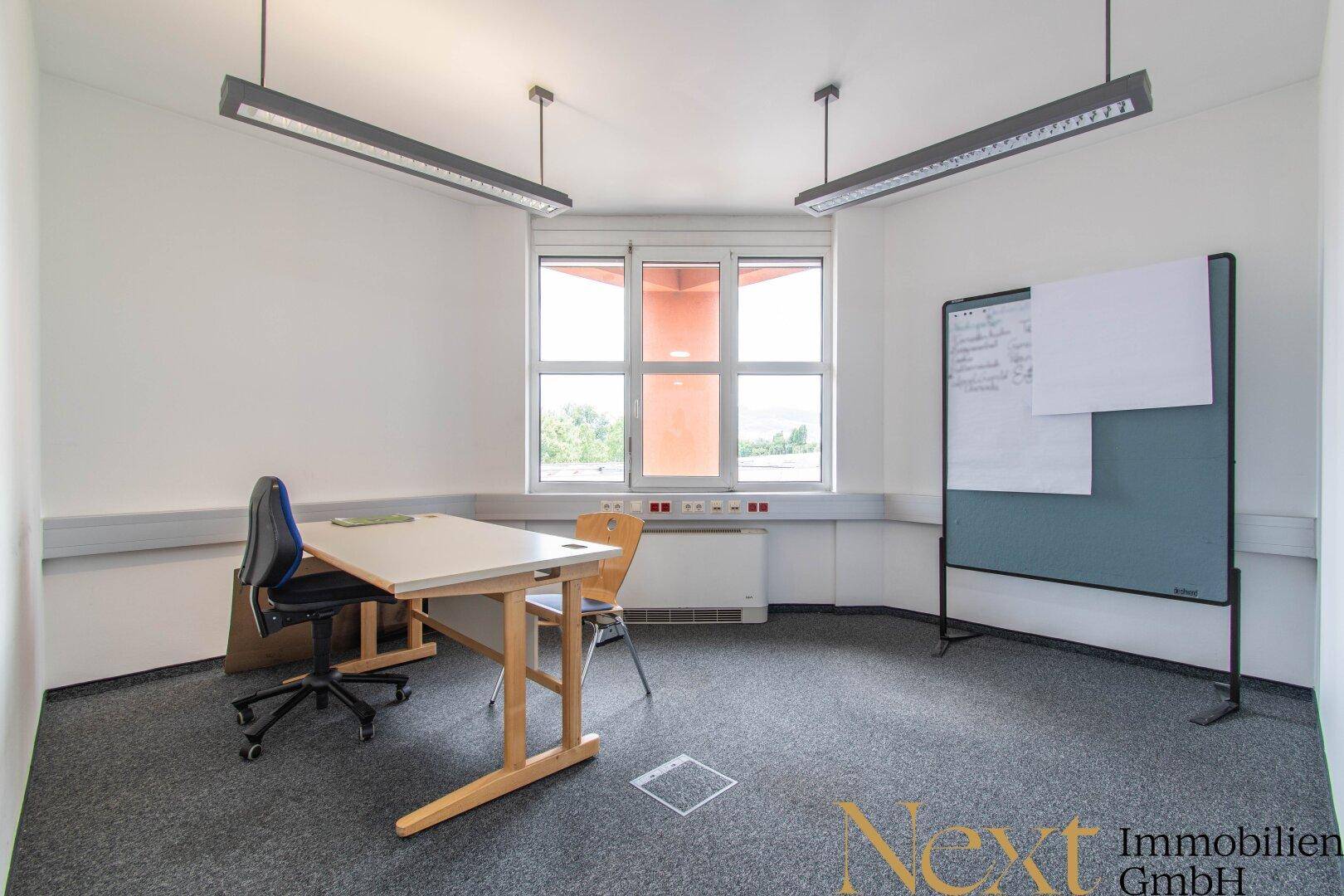 Kleinerer Büroraum mit einem Schreibtisch, Bürostuhl und Whiteboard, ideal für Einzelarbeit oder Besprechungen.