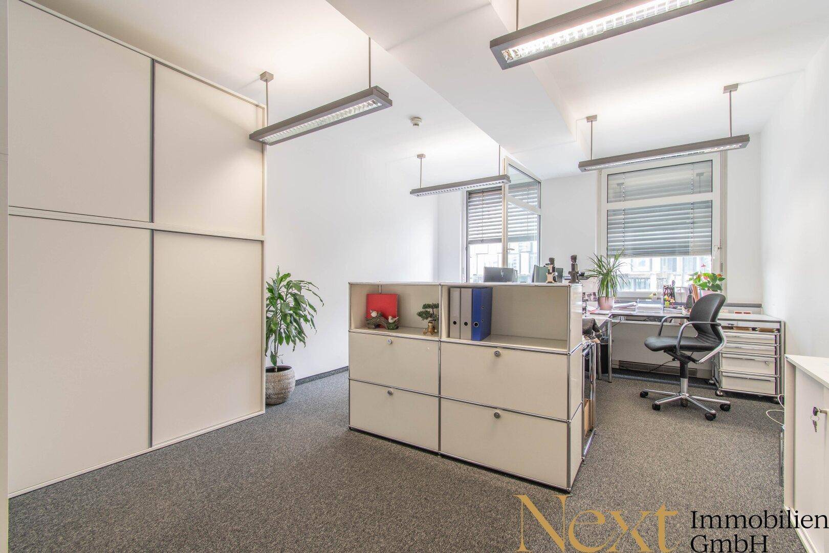 Funktionales Büro mit Teppichboden, integrierten Schränken und einem modernen Schreibtischbereich mit Tageslicht.