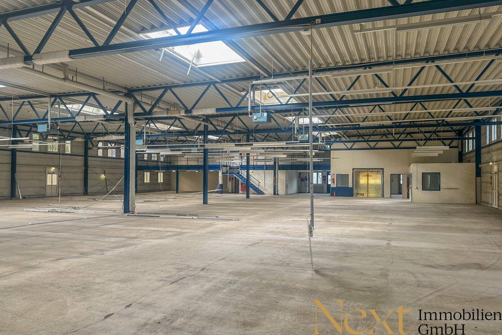 Weitläufige Industriehalle mit hohen Decken, Oberlichtern und einem robusten Betonboden.