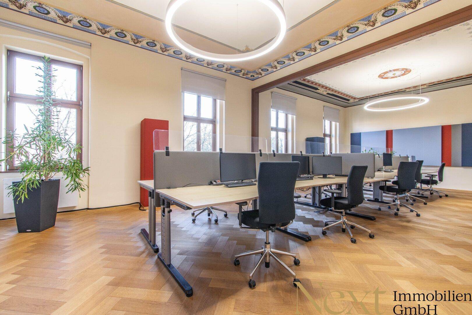 Großes, offenes Büro mit mehreren Arbeitsplätzen, Fischgrätparkett und dekorativer Deckenmalerei.