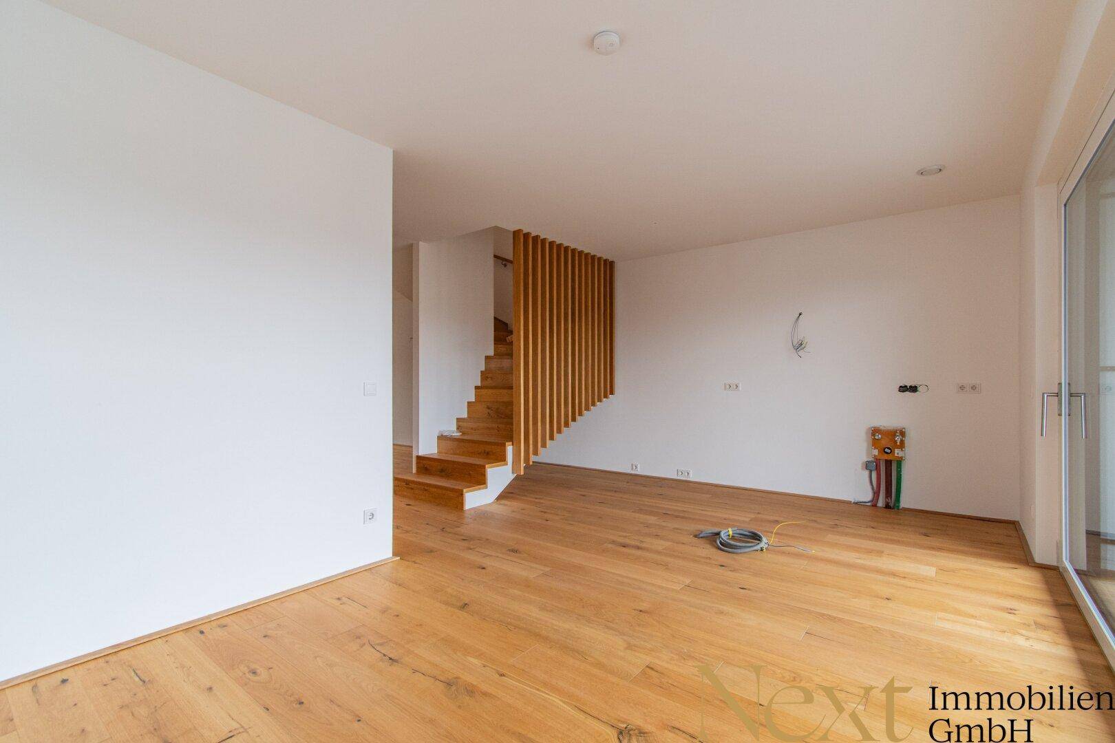Heller Wohnbereich mit Holztreppe und Parkettboden, bereit für die individuelle Gestaltung.