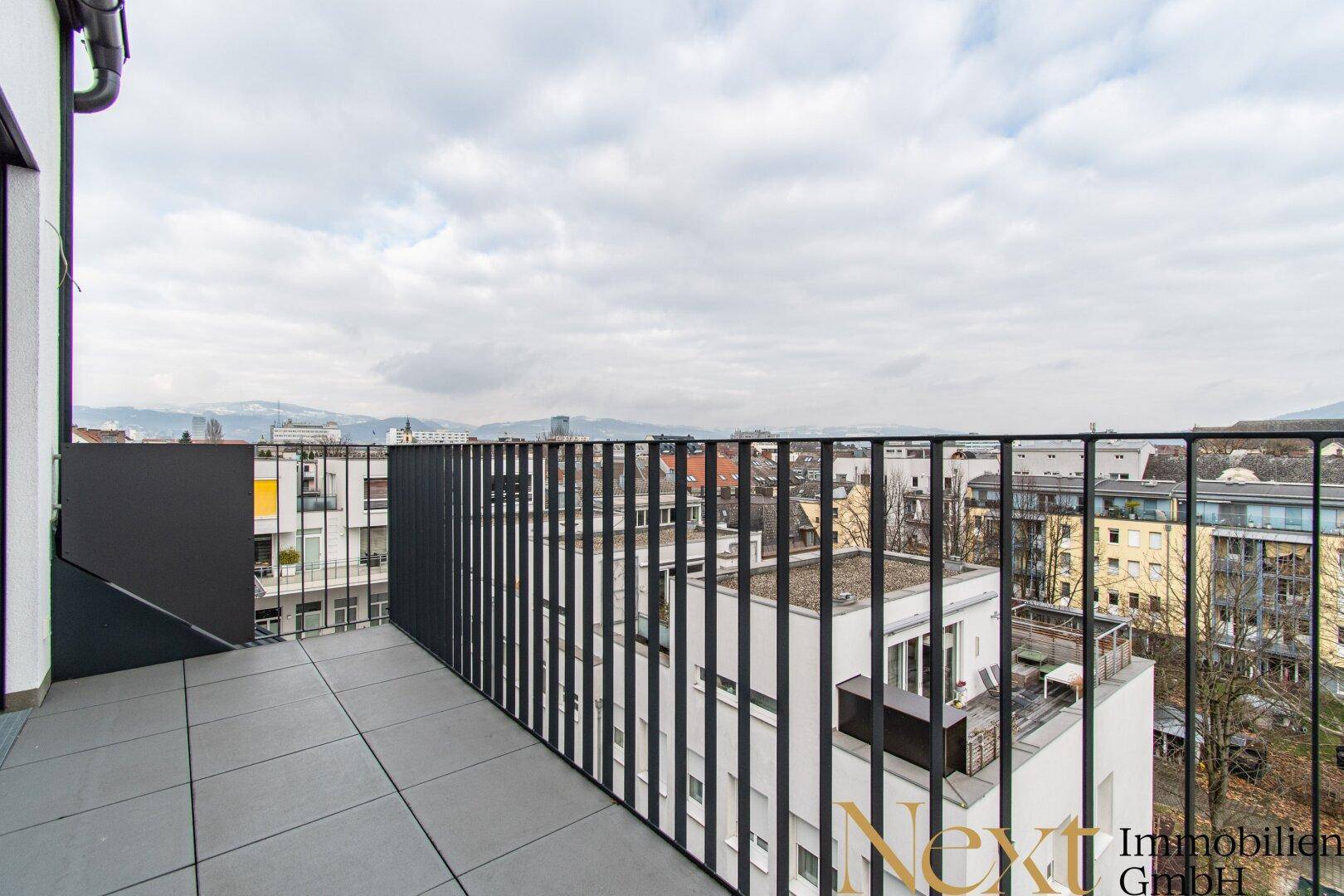 Große Terrasse mit Metallgeländer und weitem Blick über die städtische Umgebung.