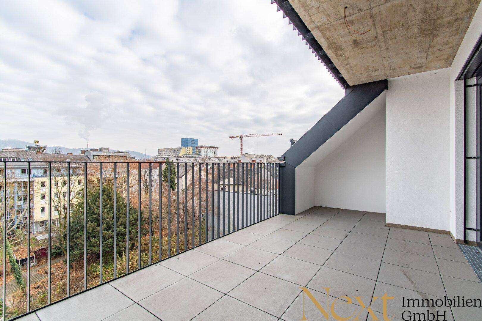 Geräumige Dachterrasse mit Fliesenboden und Blick über die Stadt.