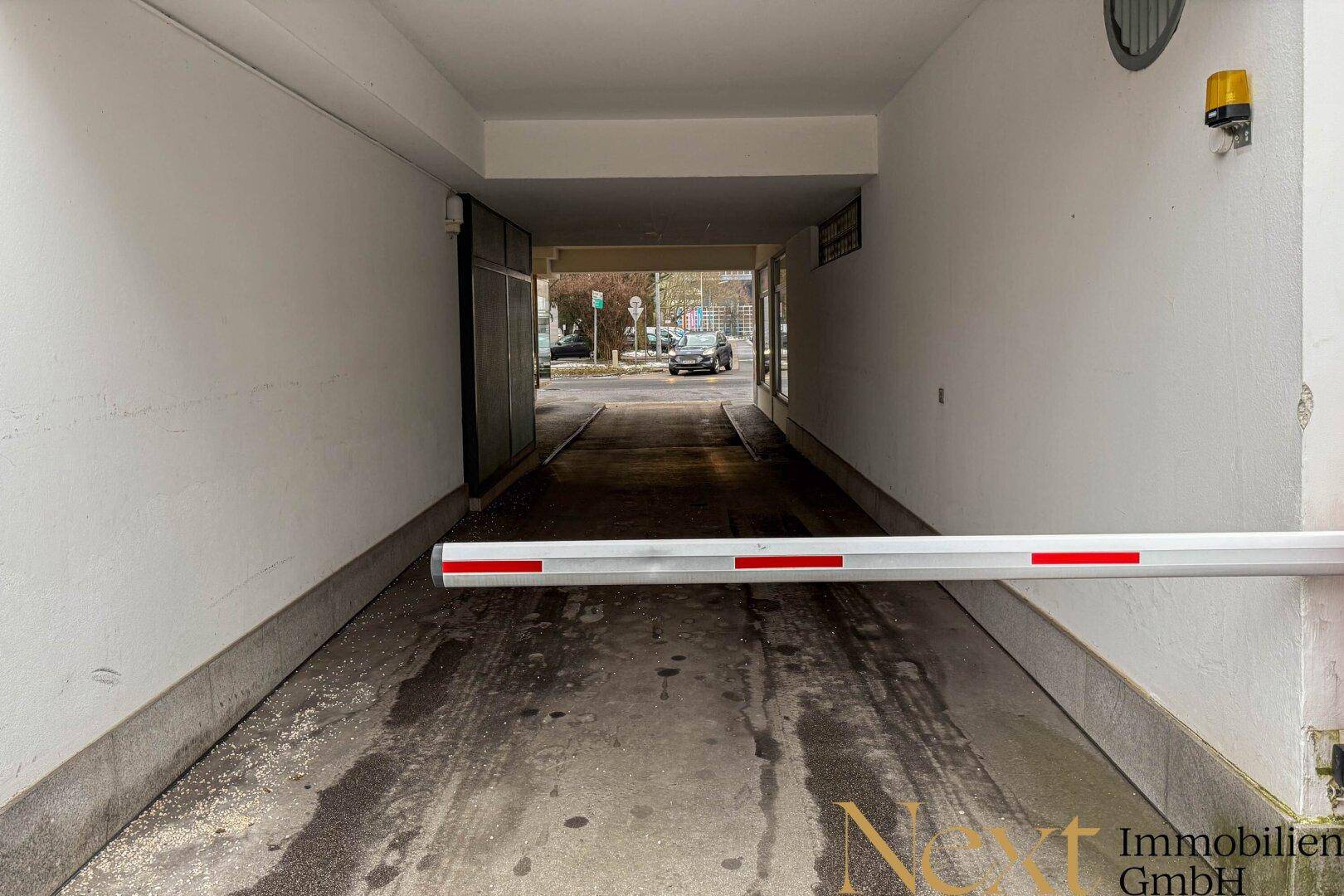 Einfahrt zu einer Tiefgarage mit Schranke und Rampe für Fahrzeuge.