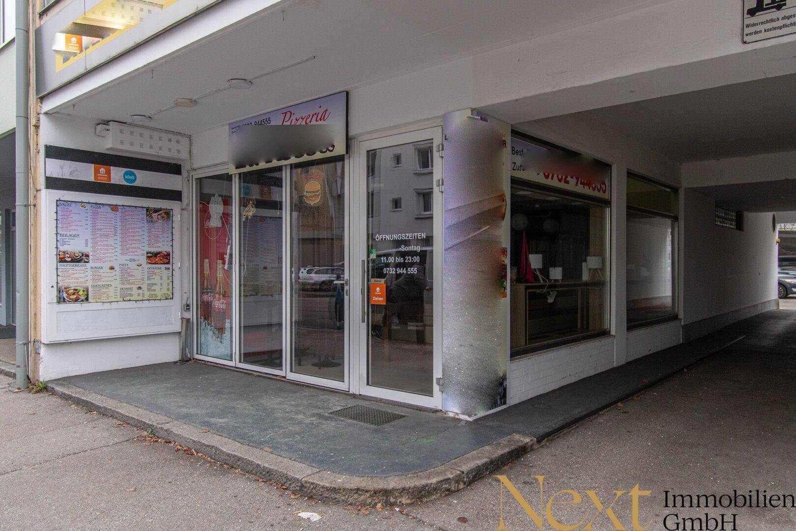 Moderne Ladenfront eines Gewerbeobjekts mit großen Glasfenstern und barrierefreiem Zugang.