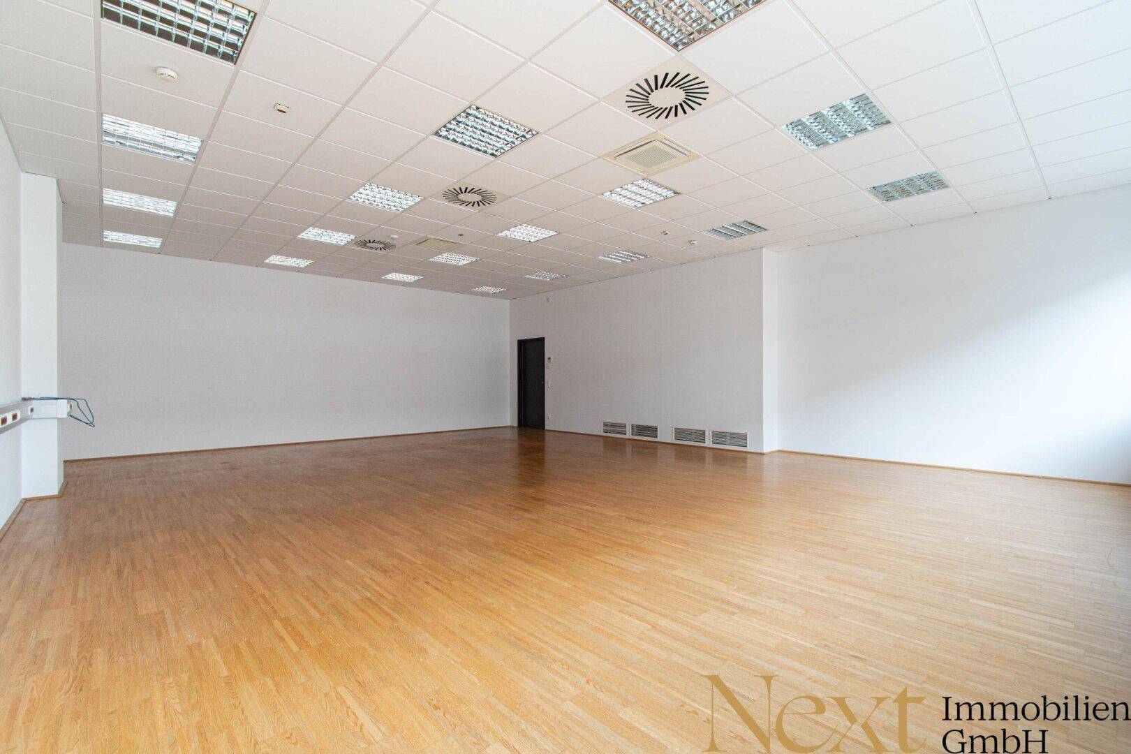 Heller, leerer Büroraum mit Holzboden und weiß gestrichenen Wänden, ideal für flexible Bürolösungen.