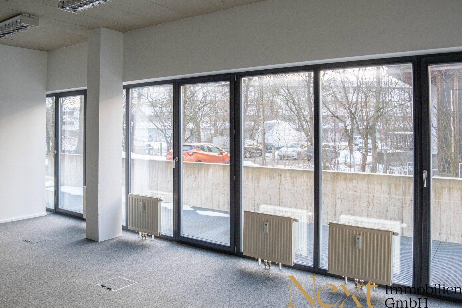 Heller Büroraum mit großen Fenstern, die einen Blick nach draußen und viel Tageslicht bieten.