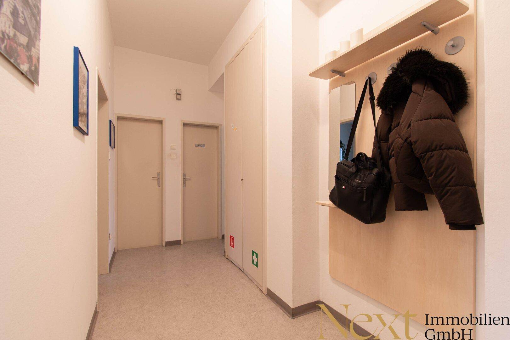 Heller Flur mit Garderobe, mehreren Türen und einem pflegeleichten Bodenbelag.