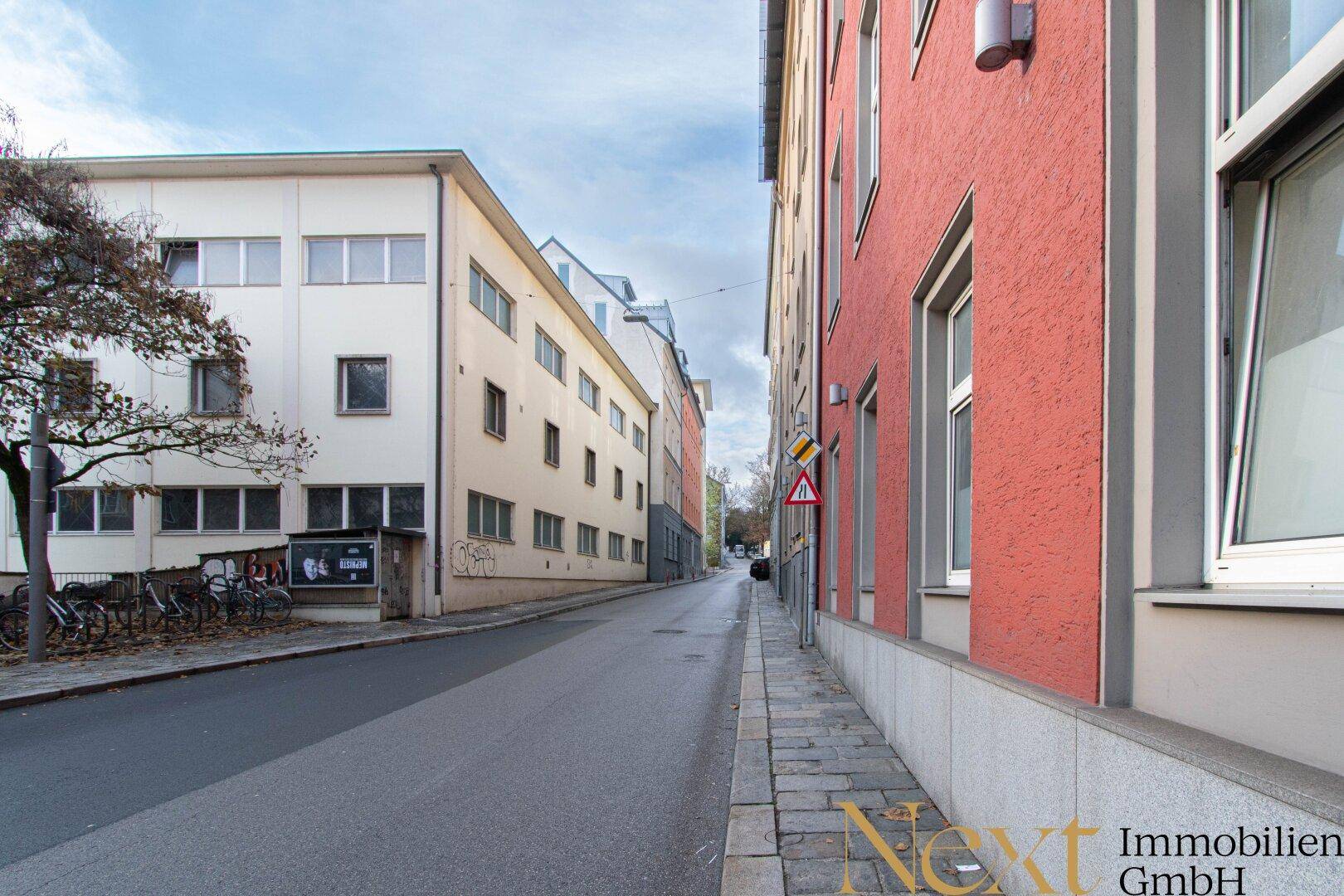 Ruhige Seitenstraße mit mehrstöckigen Gebäuden und geparkten Fahrrädern an einem Herbsttag.