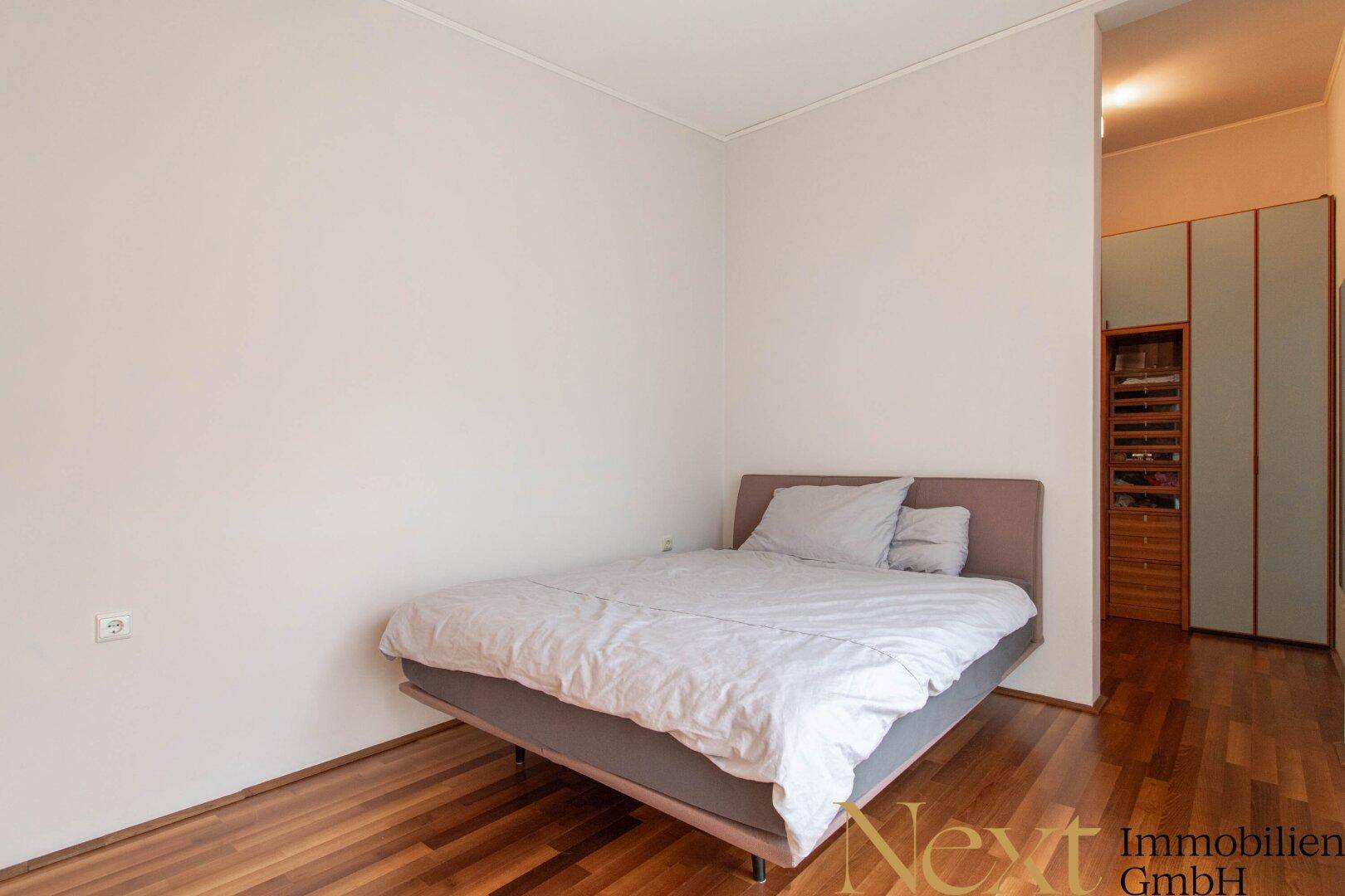Ruhiges Schlafzimmer mit Holzboden, weiß gestrichenen Wänden und integriertem Kleiderschrank.