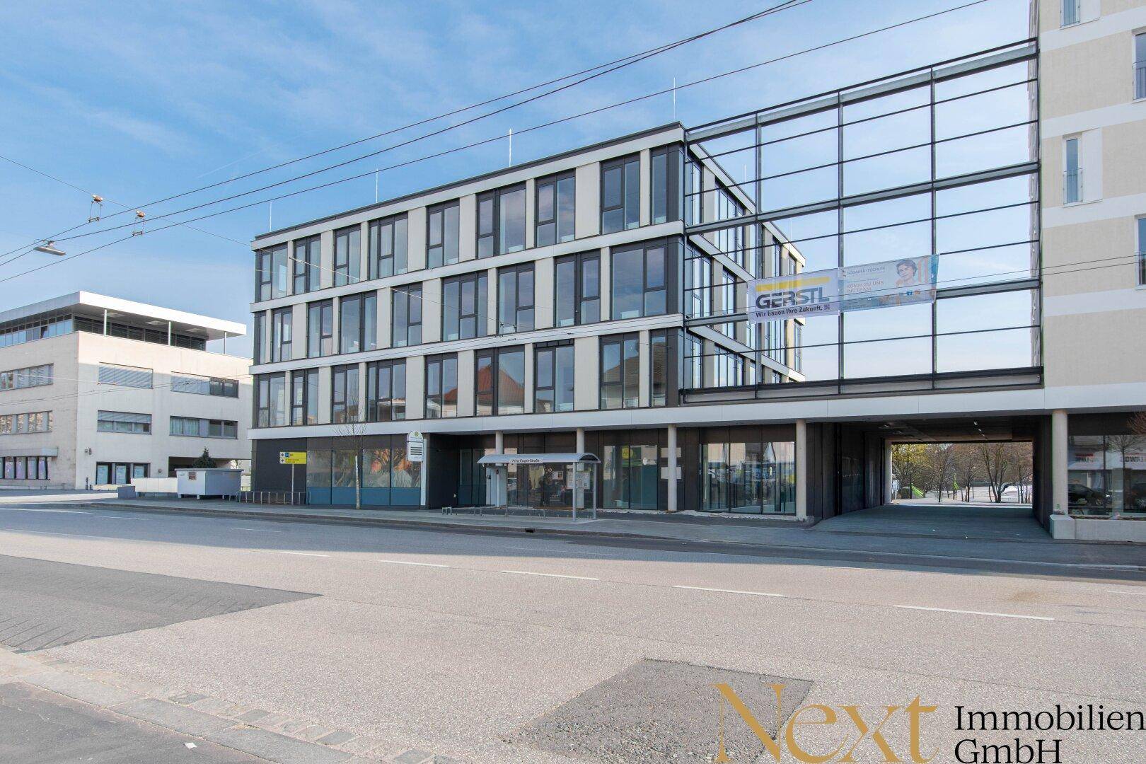 Modernes Geschäftsgebäude mit Glasfassade und klaren Linien an einer städtischen Straße.