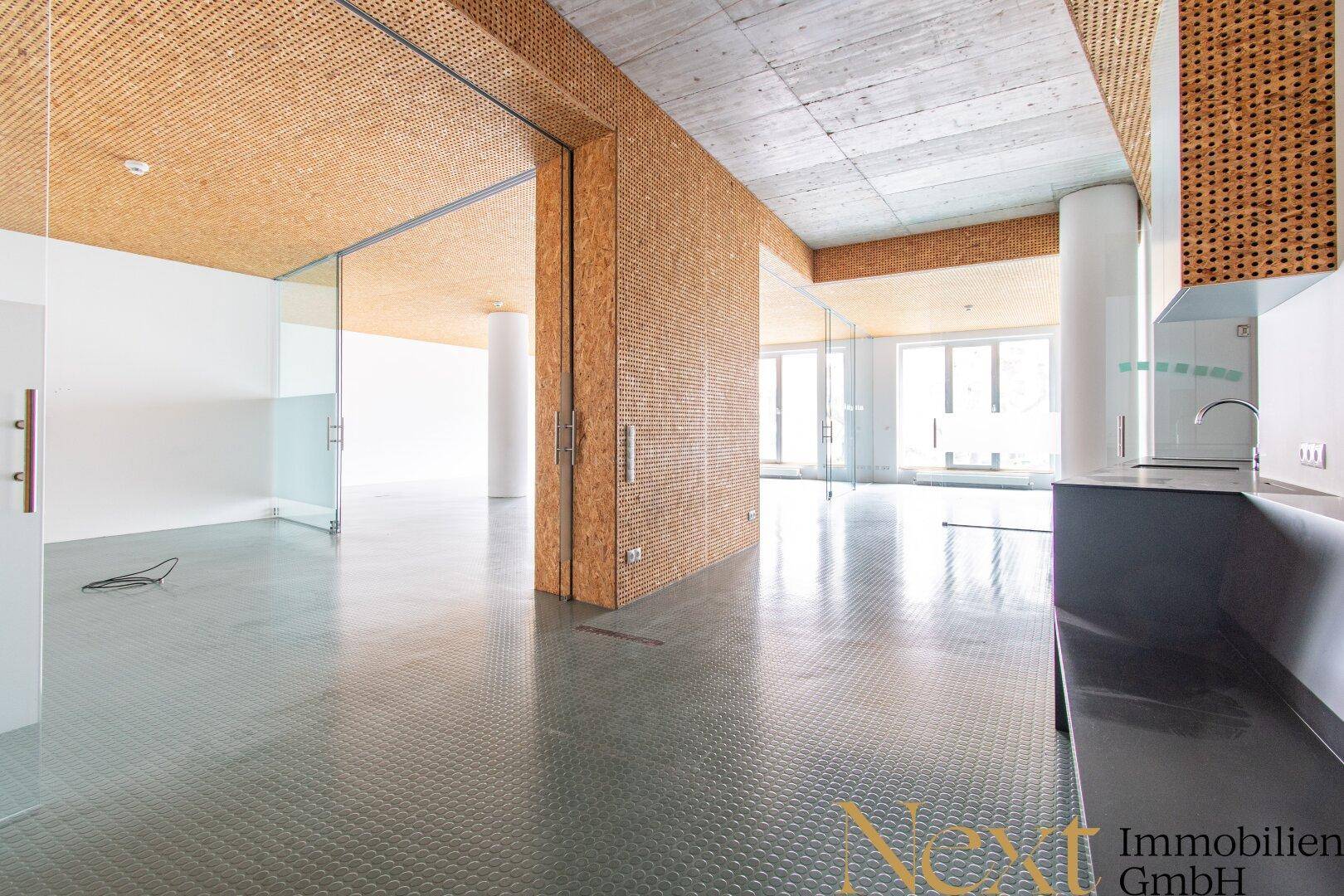 Moderner Küchenbereich in einem offenen Raum mit OSB-Decke und Betonakzenten, ideal für Pausen.
