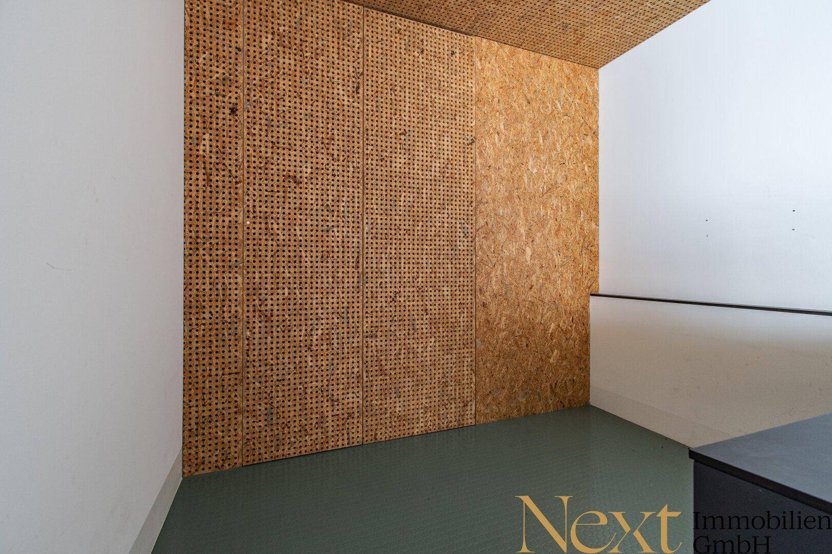 Detailansicht einer Wand mit OSB-Plattenverkleidung und weiß gestrichenen Bereichen in einem Innenraum.