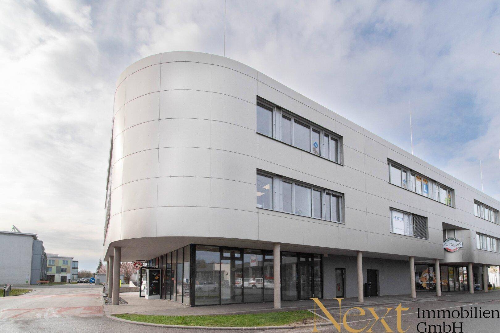 Modernes Geschäftsgebäude mit geschwungener Fassade und großen Fensterflächen.