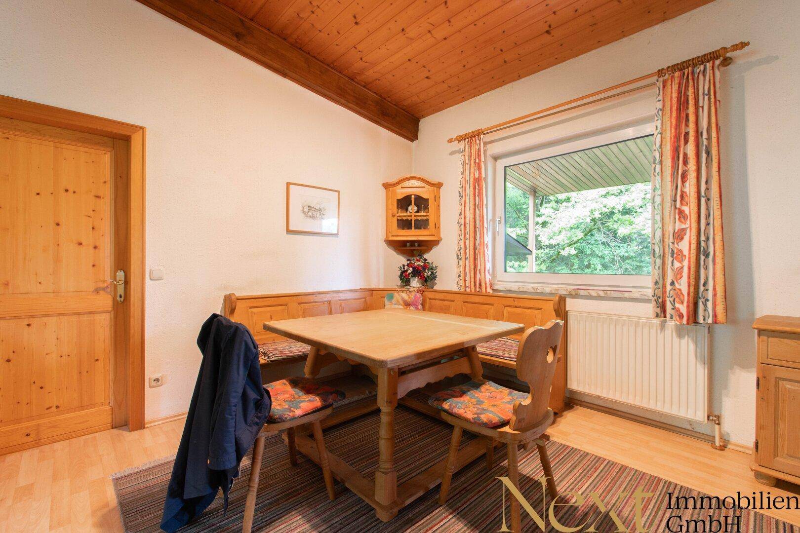 Traditioneller Essbereich mit Eckbank und Holztisch, ideal für Familienmahlzeiten, mit Blick ins Grüne.