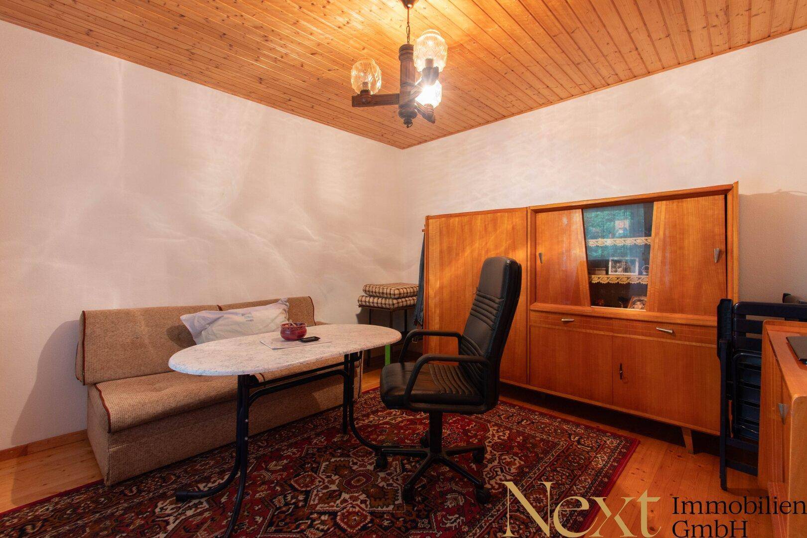 Arbeitszimmer mit Schreibtisch, Sofa und einem großen Holzschrank, ideal für Home-Office oder als Gästezimmer.