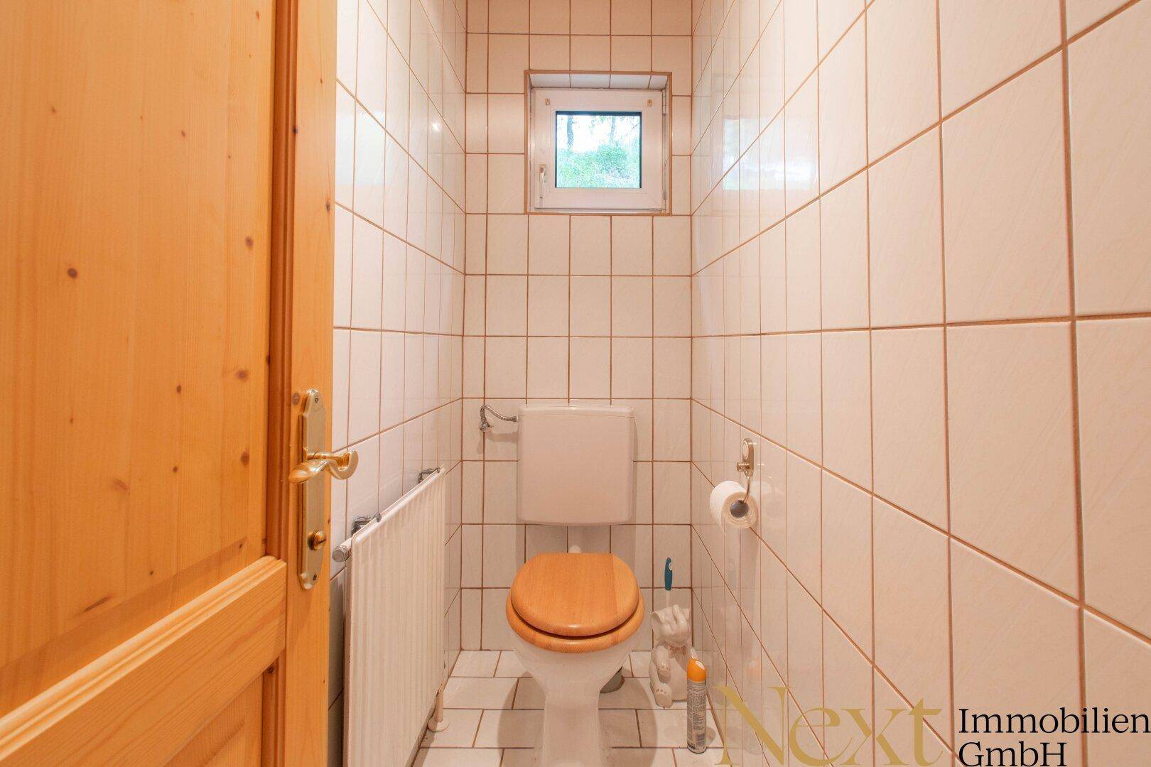 Separates Gäste-WC mit Fenster, Toilette und Fliesenboden, praktisch und gut gepflegt.