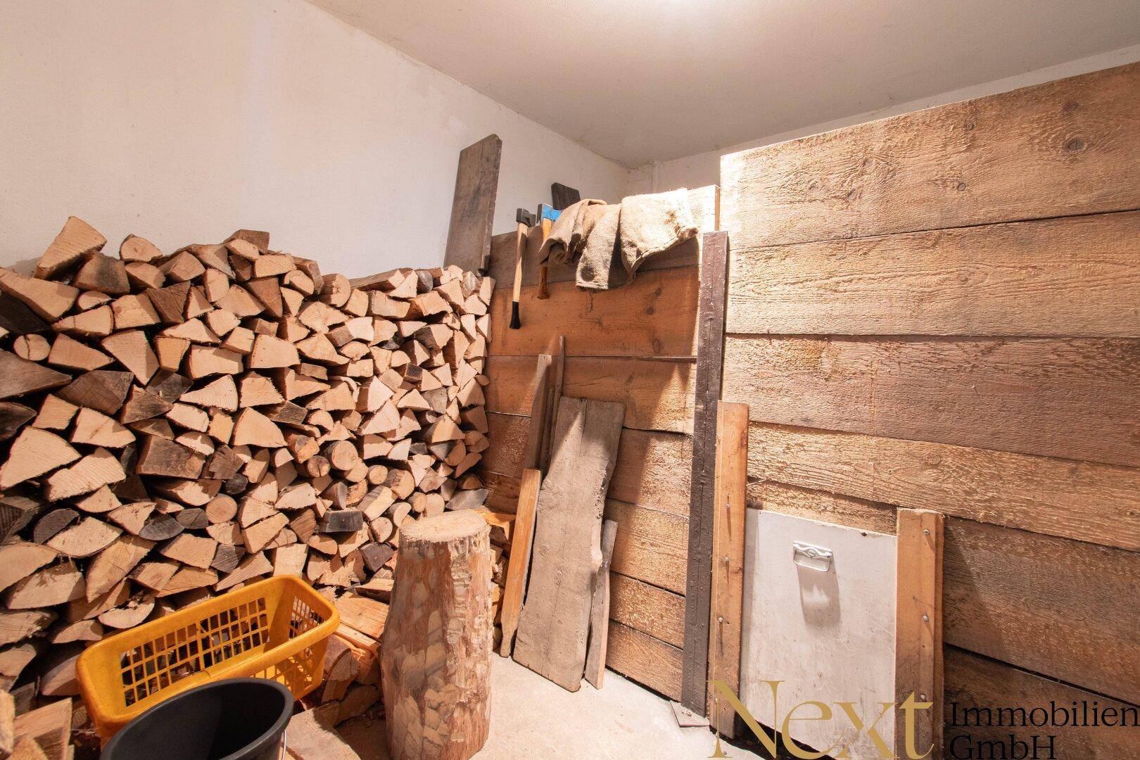Praktischer Lagerraum für Brennholz im Keller, mit gestapeltem Holz und Holzverkleidung an den Wänden.