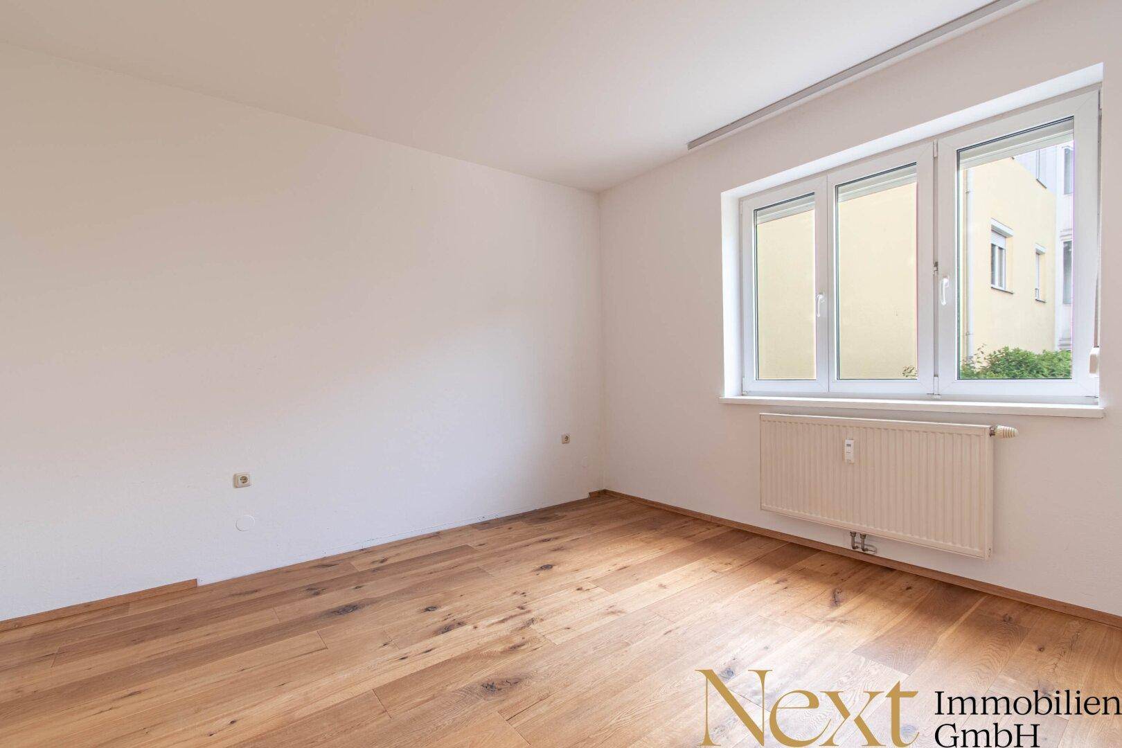 Helles Schlafzimmer mit Holzfußboden und großem Fenster.