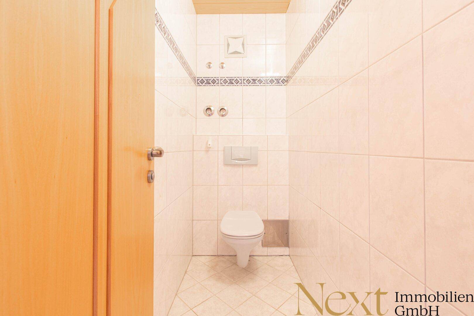 Separates WC mit Wand-WC und Fliesenboden.