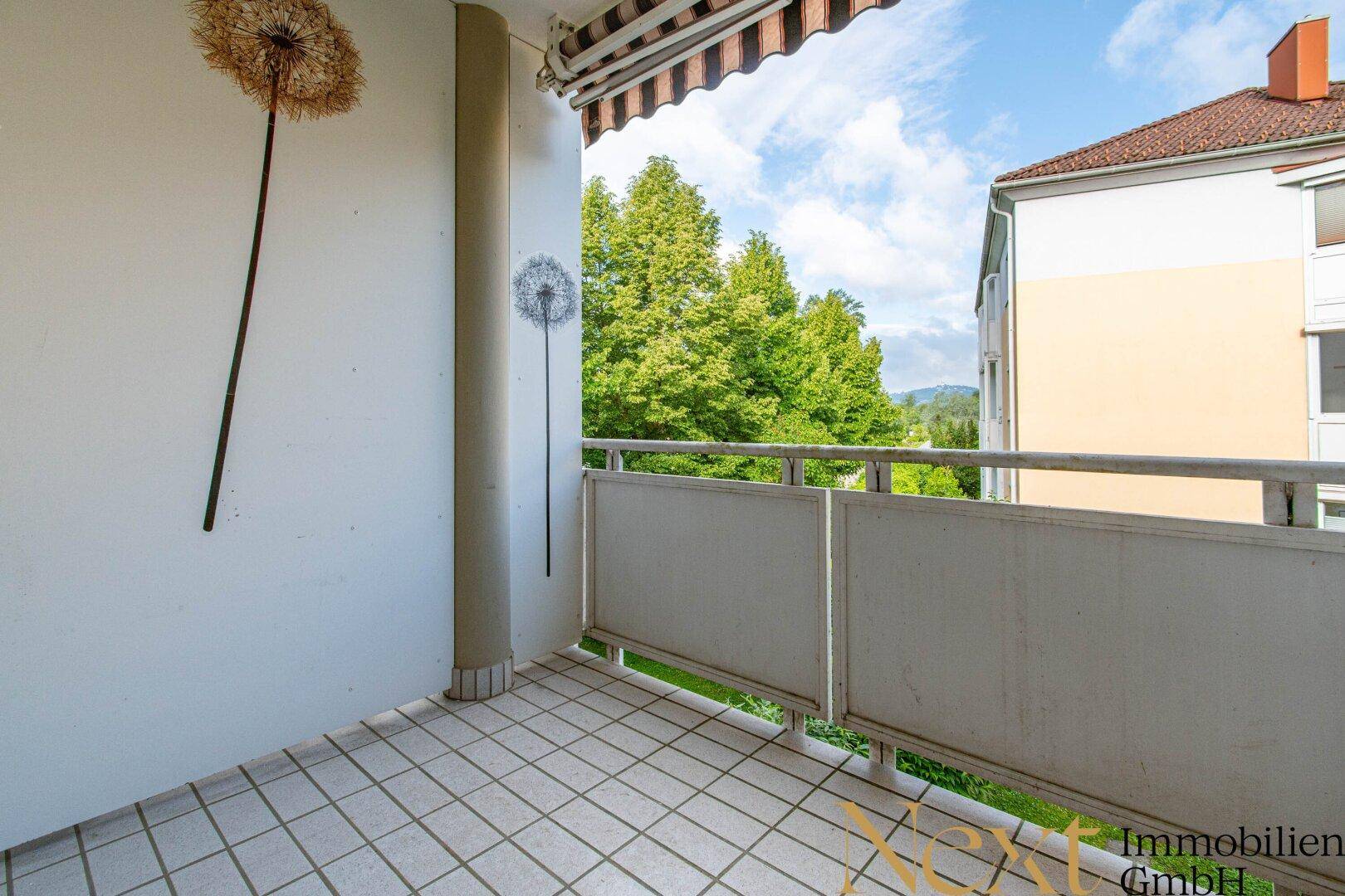 Gemütlicher Balkon mit Fliesenboden und Blick ins Grüne.
