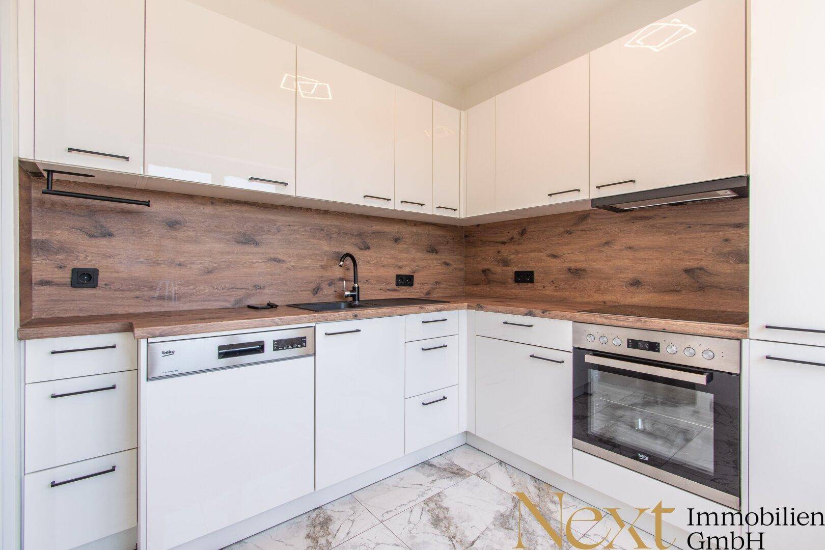 Moderne Einbauküche mit weißen Hochglanzfronten, Holzoptik-Arbeitsplatten und integrierten Geräten.