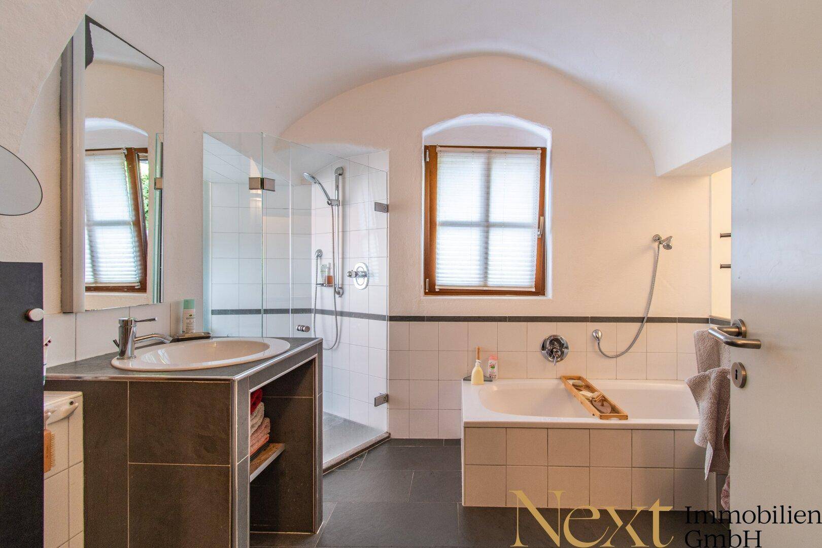 Modernes Badezimmer mit Badewanne, Duschkabine, Einzelwaschbecken und gewölbter Decke.
