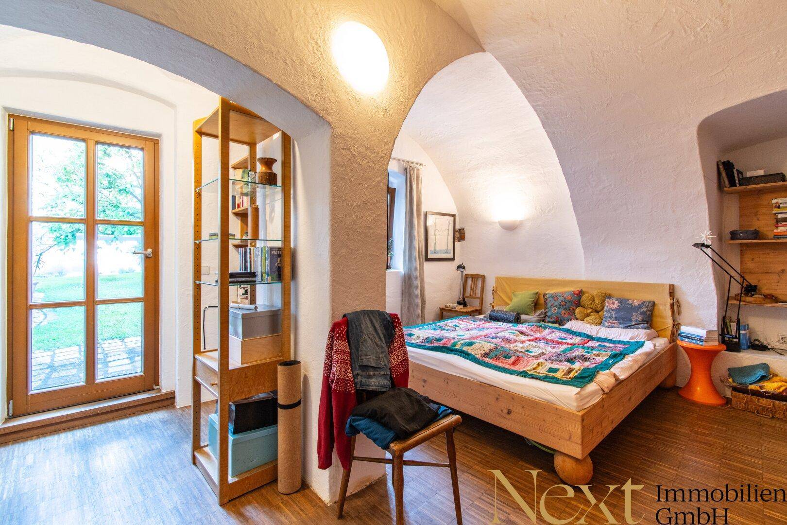 Gemütliches Schlafzimmer mit Holzbett, gewölbter Decke und direktem Zugang zum Garten.